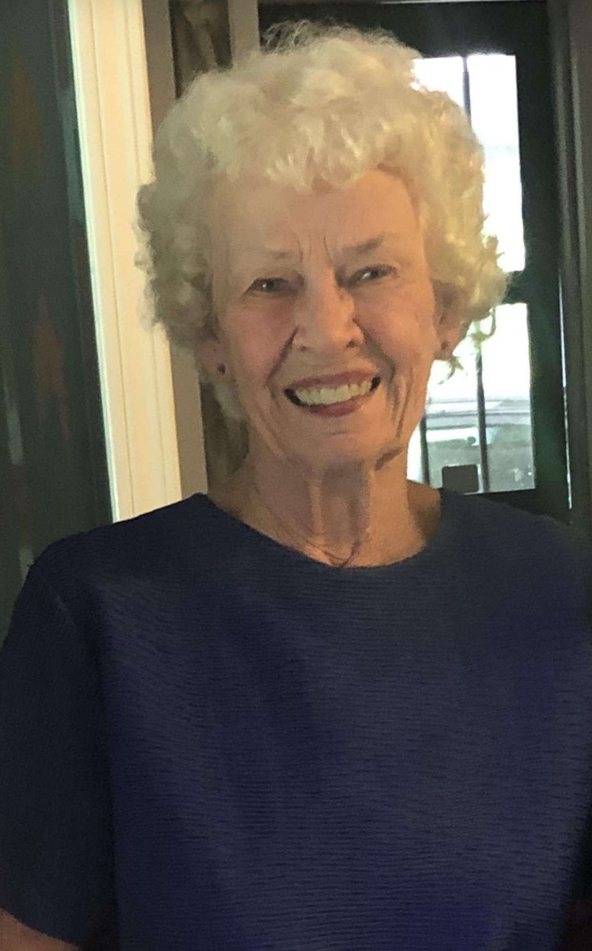 Elderly woman dressed in blue beam with a cheerful expression, showcasing her joyful demeanor.
