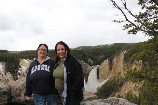 A couple of women standing on a rock with a waterfall in the background