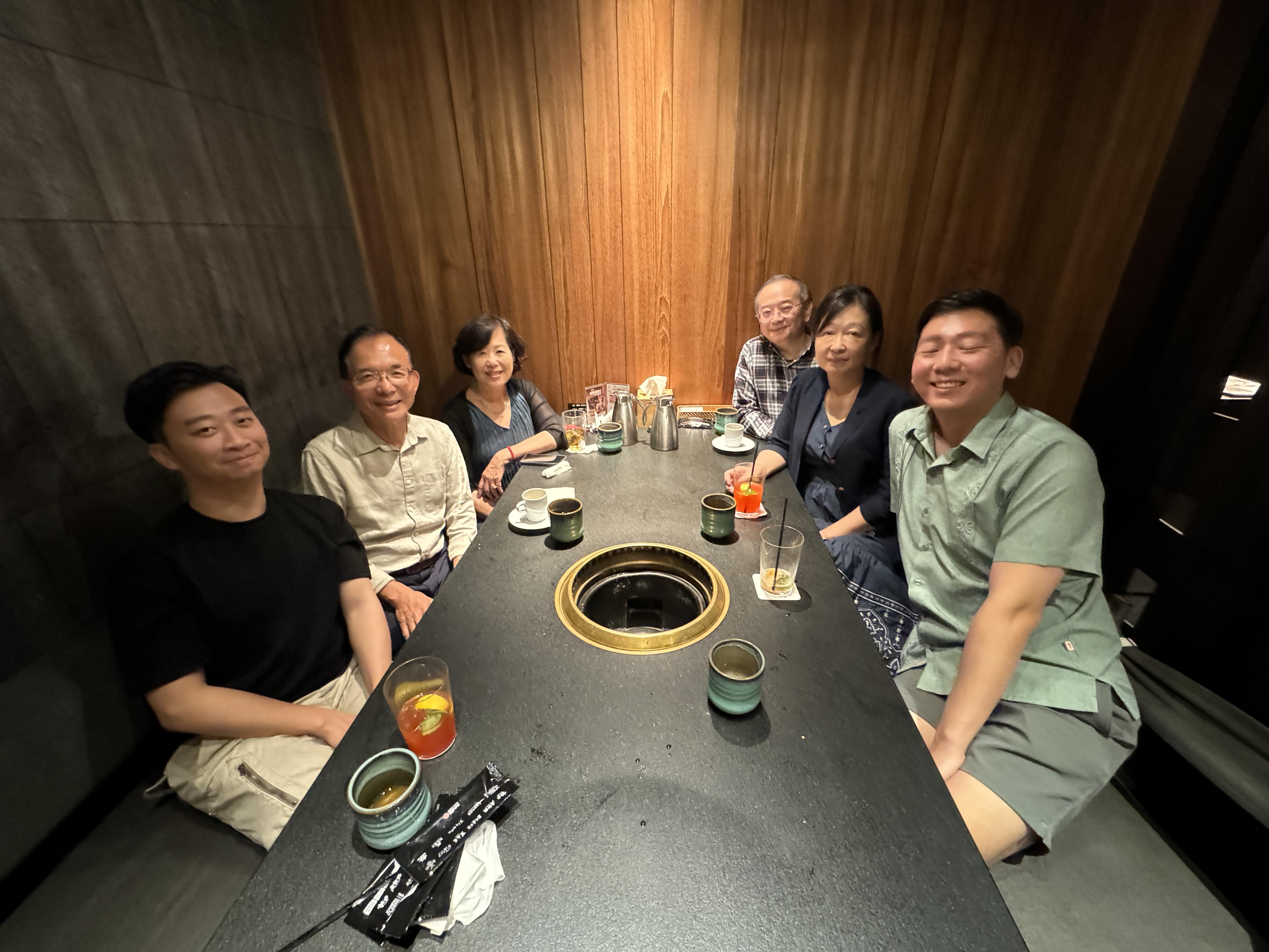 Six friends gather around a barbecue grill in a cozy restaurant, sharing food and laughter.