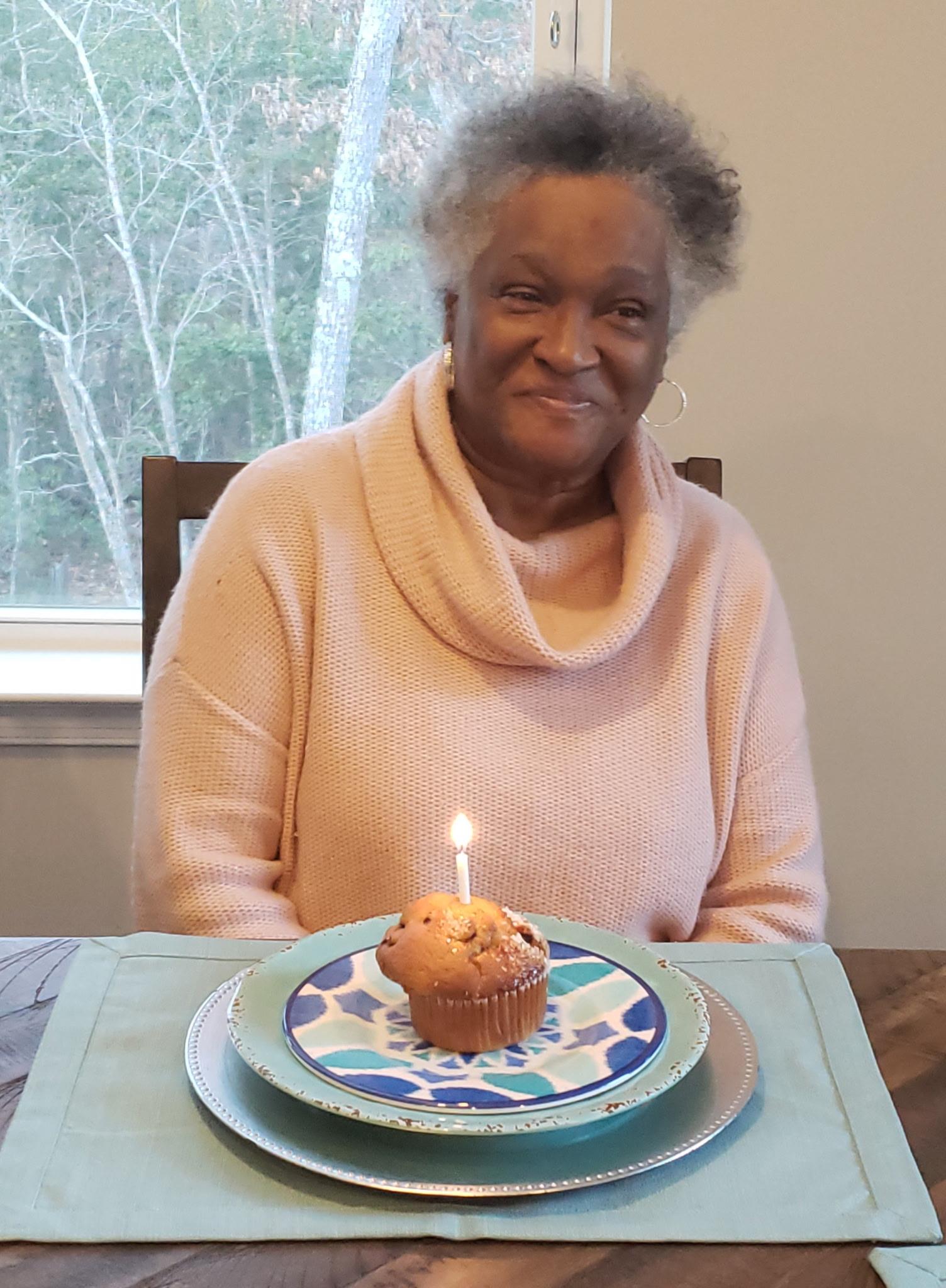 A woman sitting at a table with a cupcake and a candle