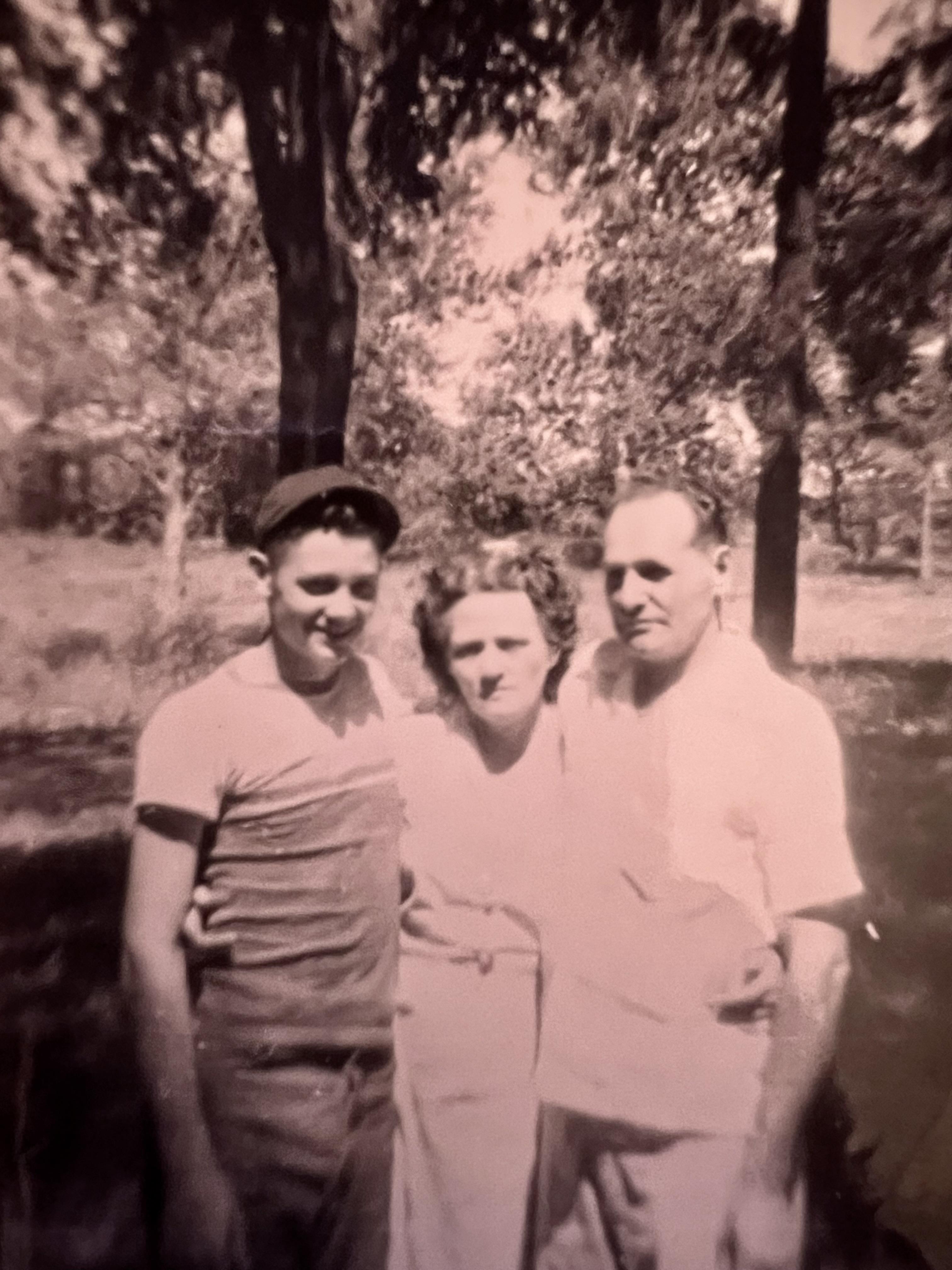 Three individuals enjoy a moment together in a sunny forest, surrounded by nature.