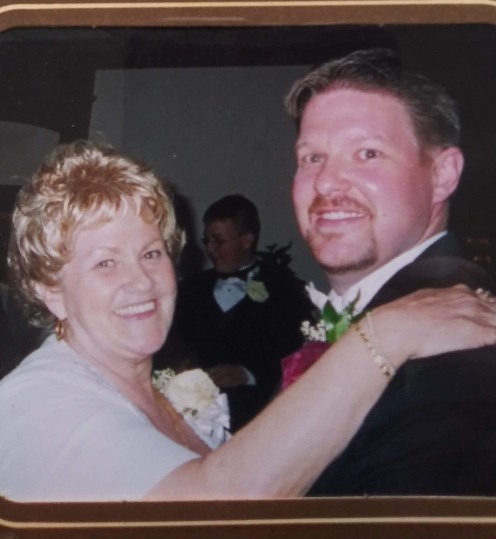 A joyful couple dances closely at a wedding reception, surrounded by guests and decorations.