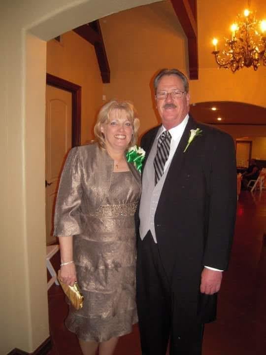 A smiling couple poses together in formal attire, enjoying a special occasion.