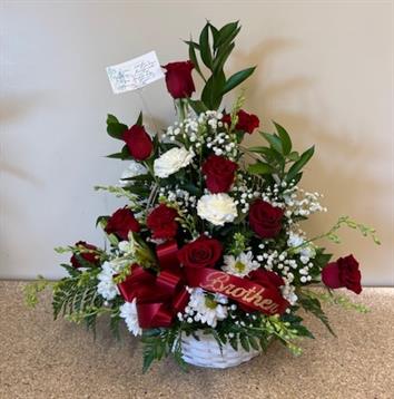 A basket of flowers with a red ribbon and a white ribbon