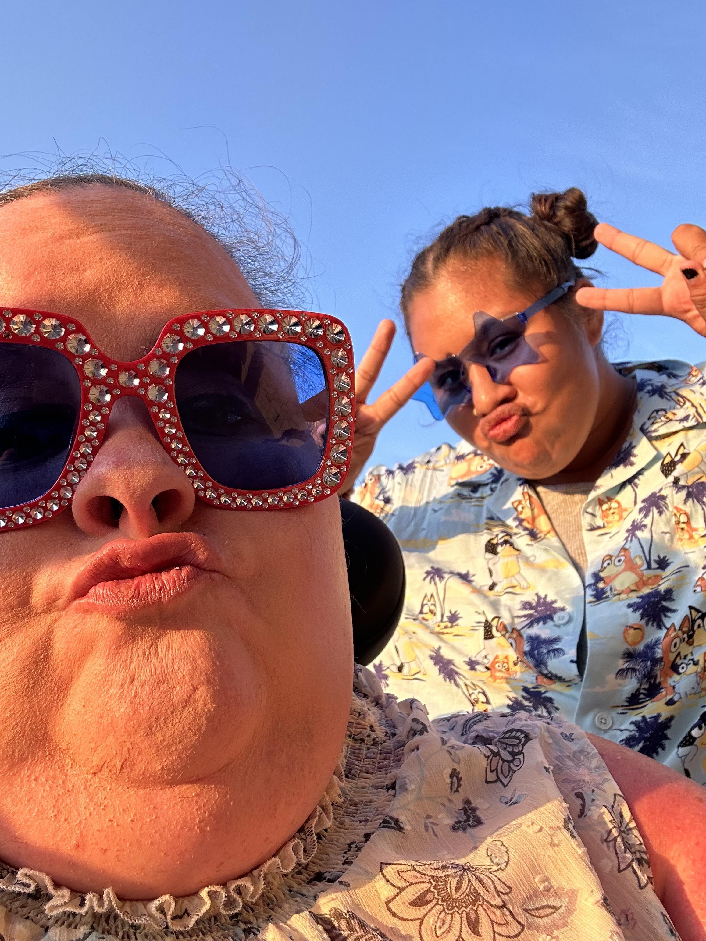 Friends have fun under a clear sky, playfully kissing the camera.