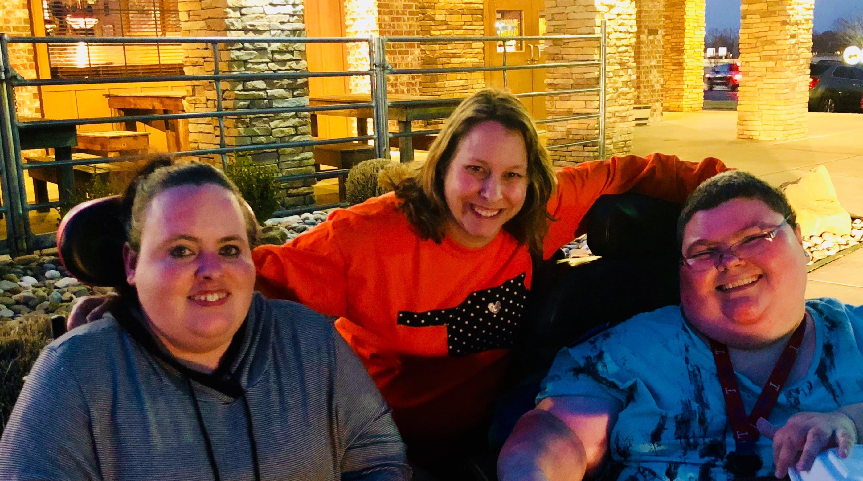 Three friends gather in a cozy outdoor setting, sharing laughter and joy at twilight.