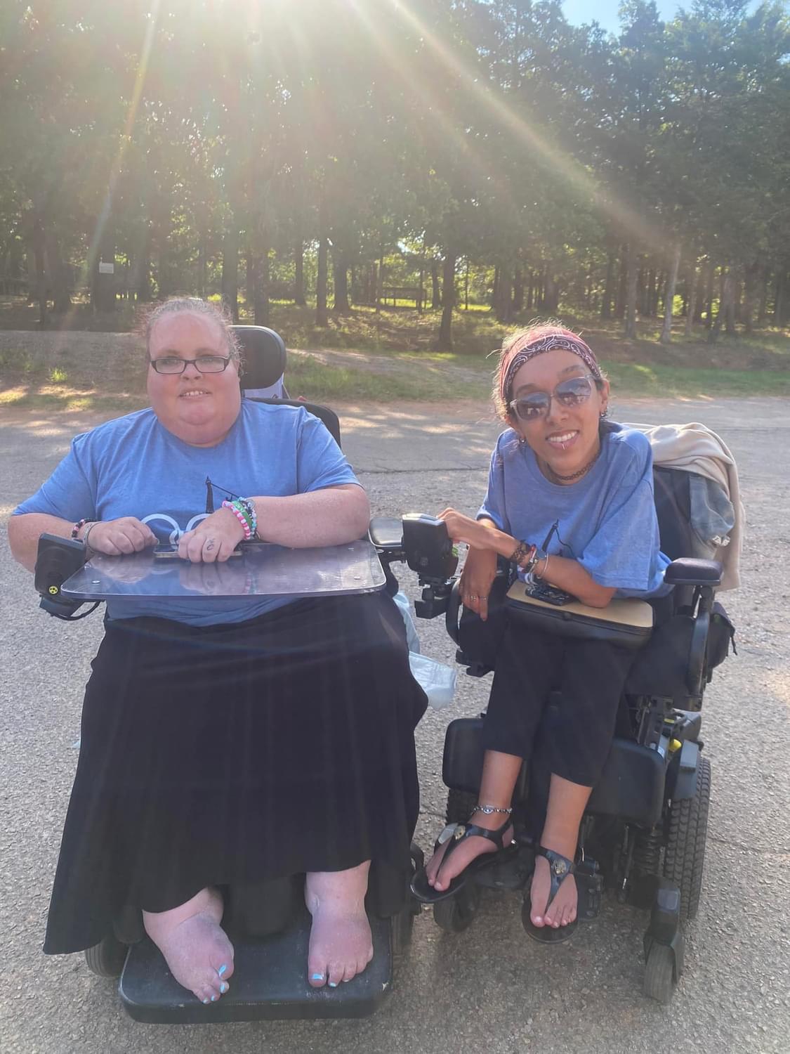 Two friends share a joyful moment outside, enjoying the sunny weather and each other's company.