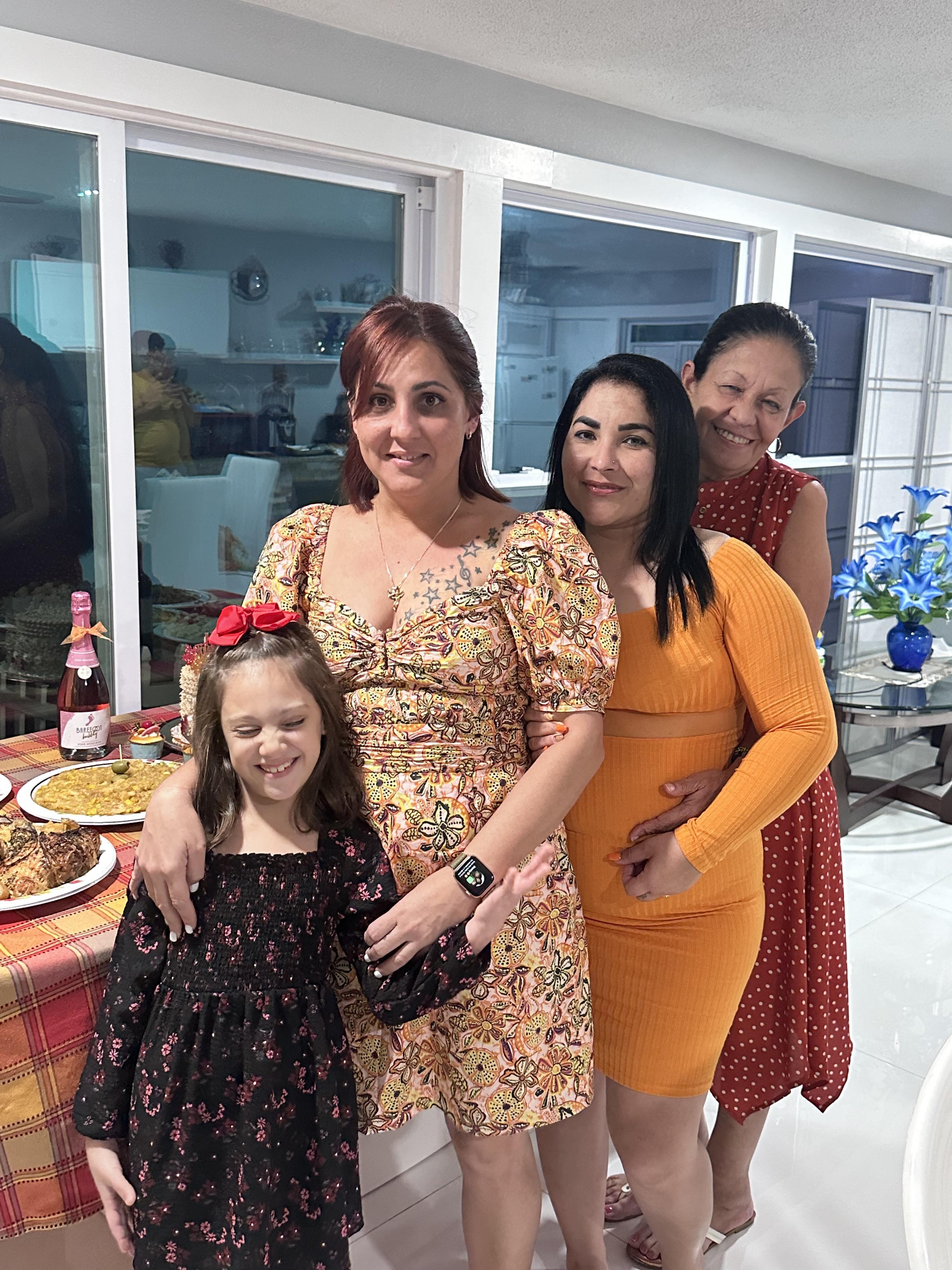 A joyful family gathering showcases women in colorful attire, sharing moments by a dining table.