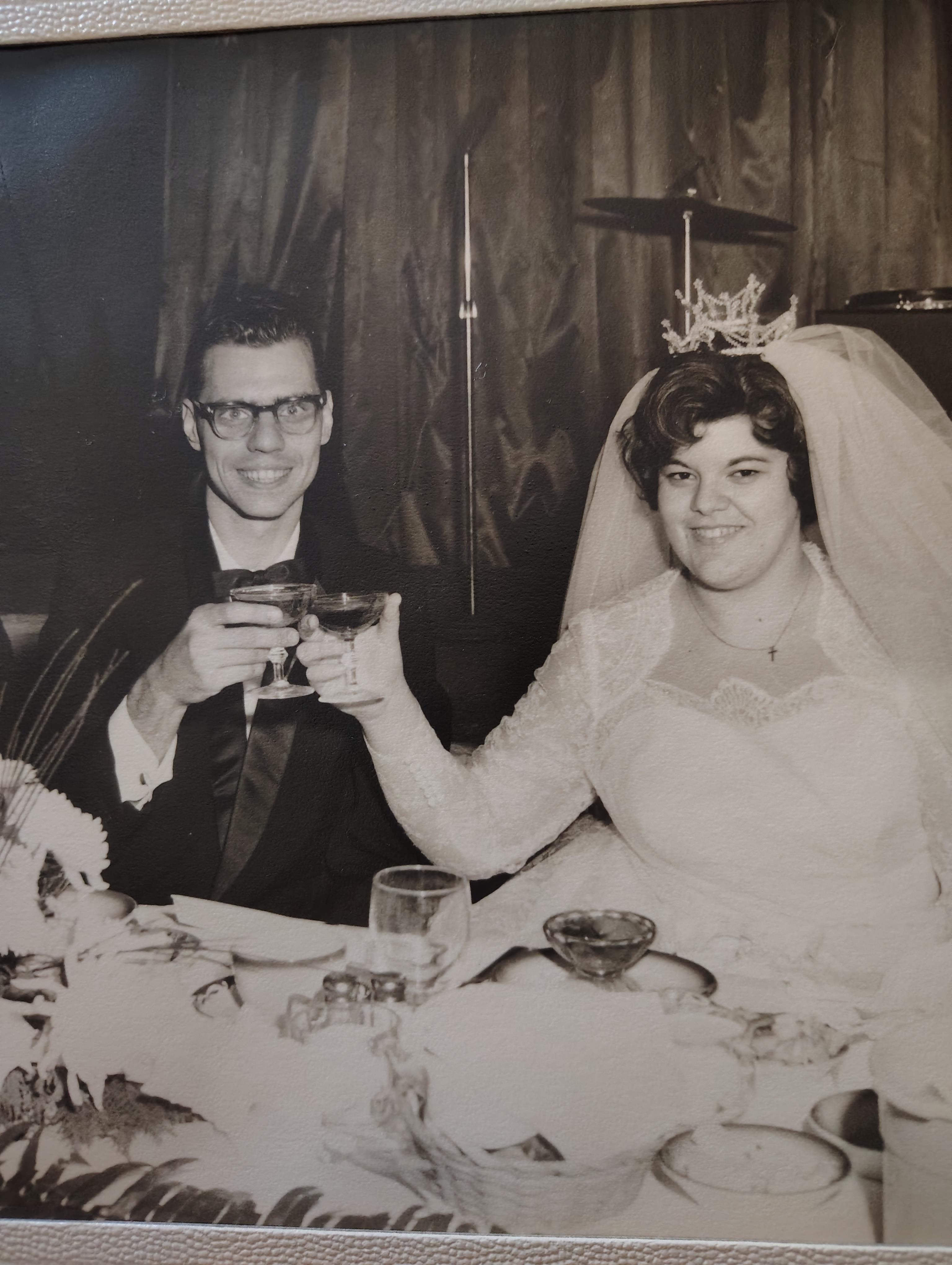 A couple toasts at their wedding reception, surrounded by festive decorations.
