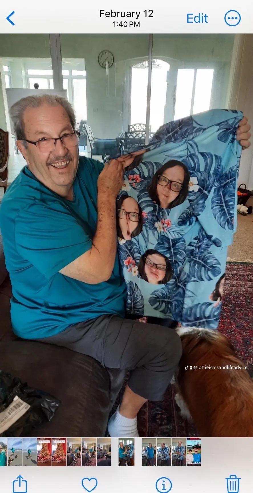 Grandfather happily displays a personalized shirt with family faces, sitting in a cozy living room.