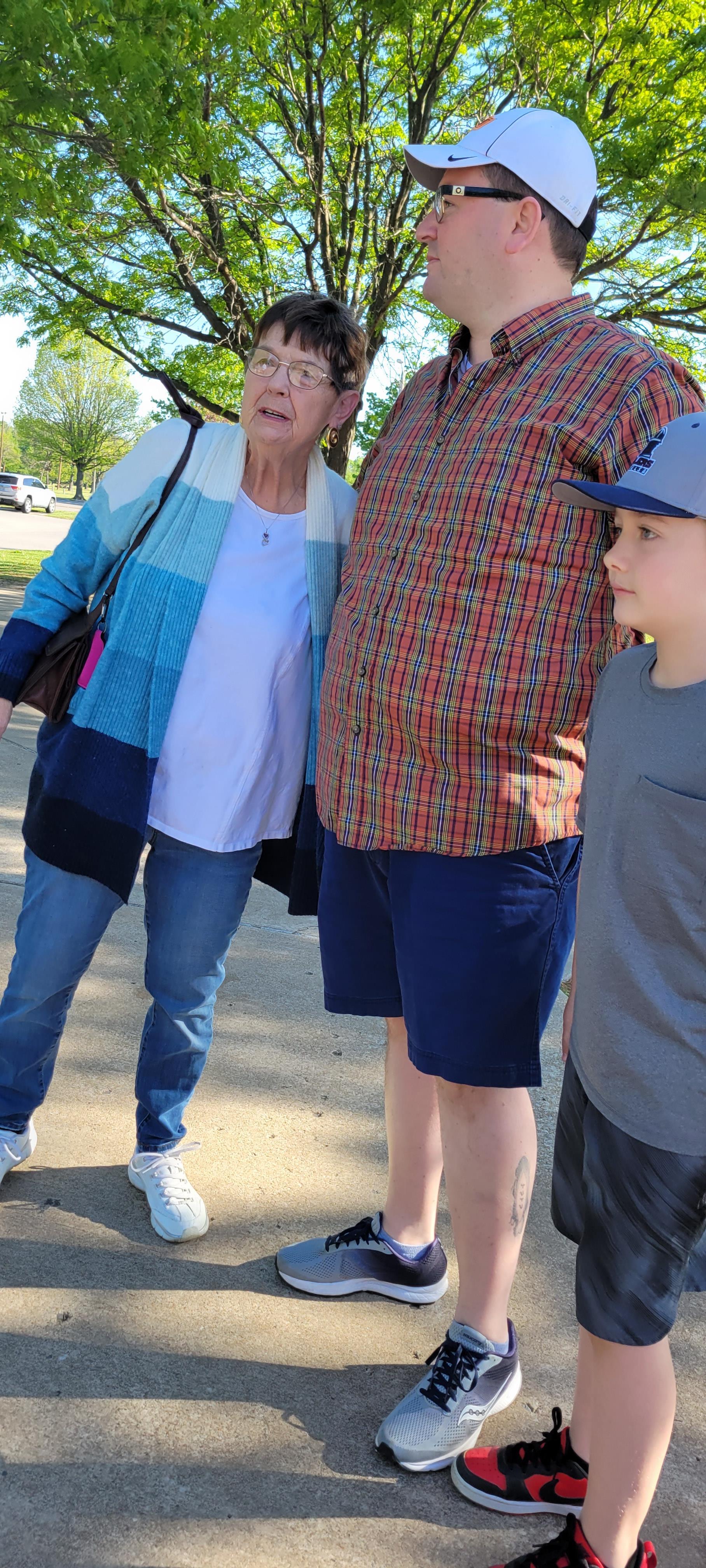 Three family members engage in conversation while enjoying a sunny afternoon outdoors.