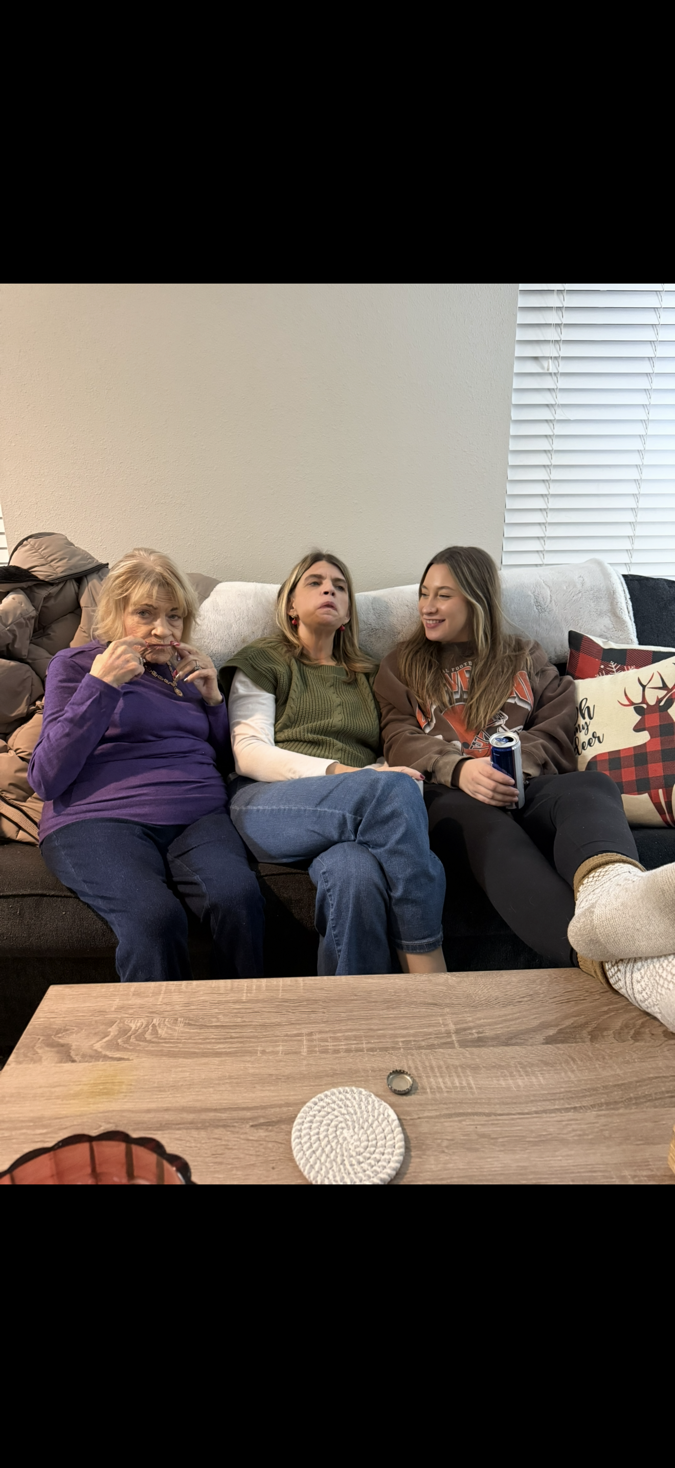 Three family members share laughter and conversation on a comfortable couch at home.