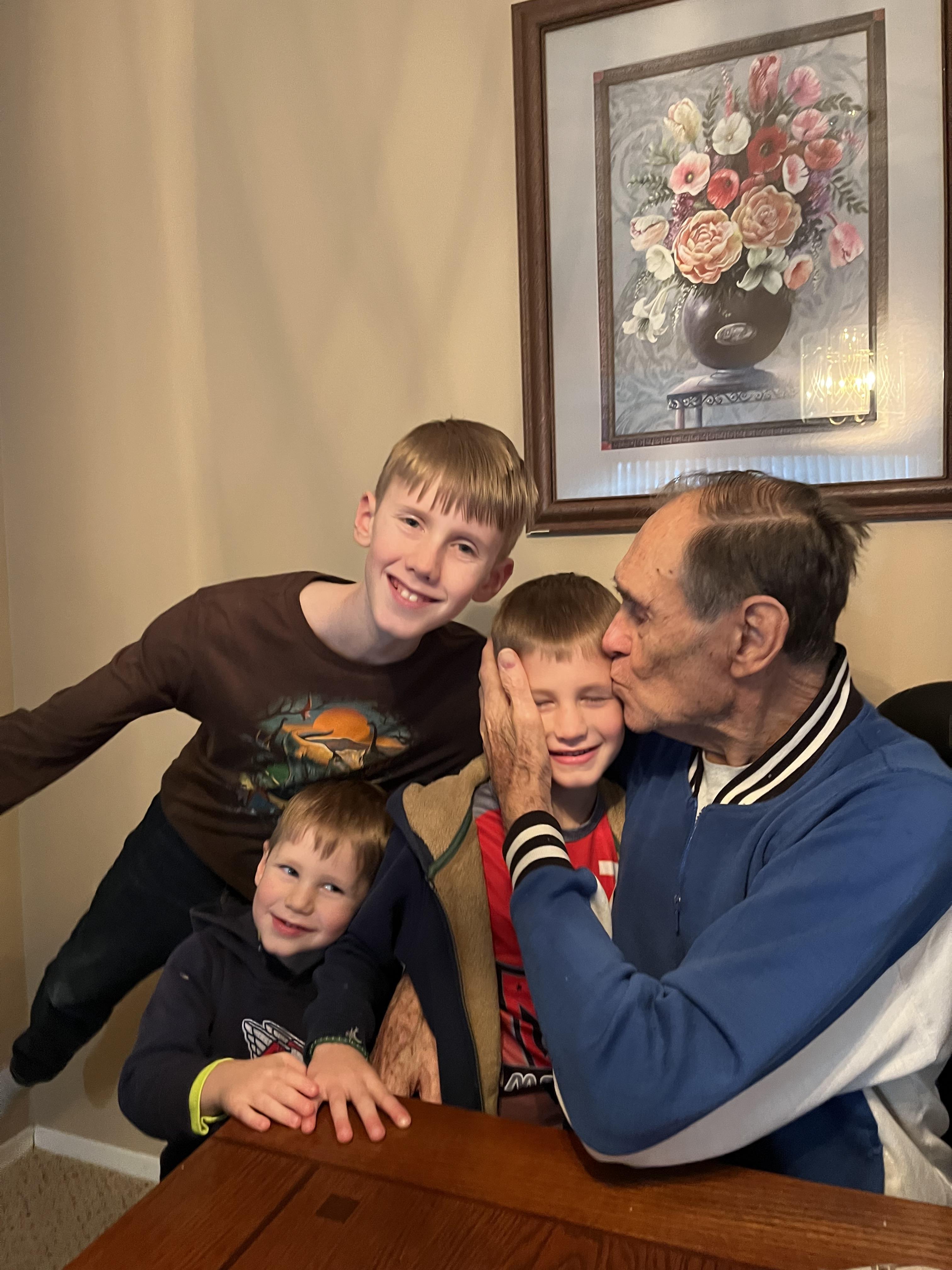 Three young boys enjoy playful moments with their grandfather at a cozy family gathering.