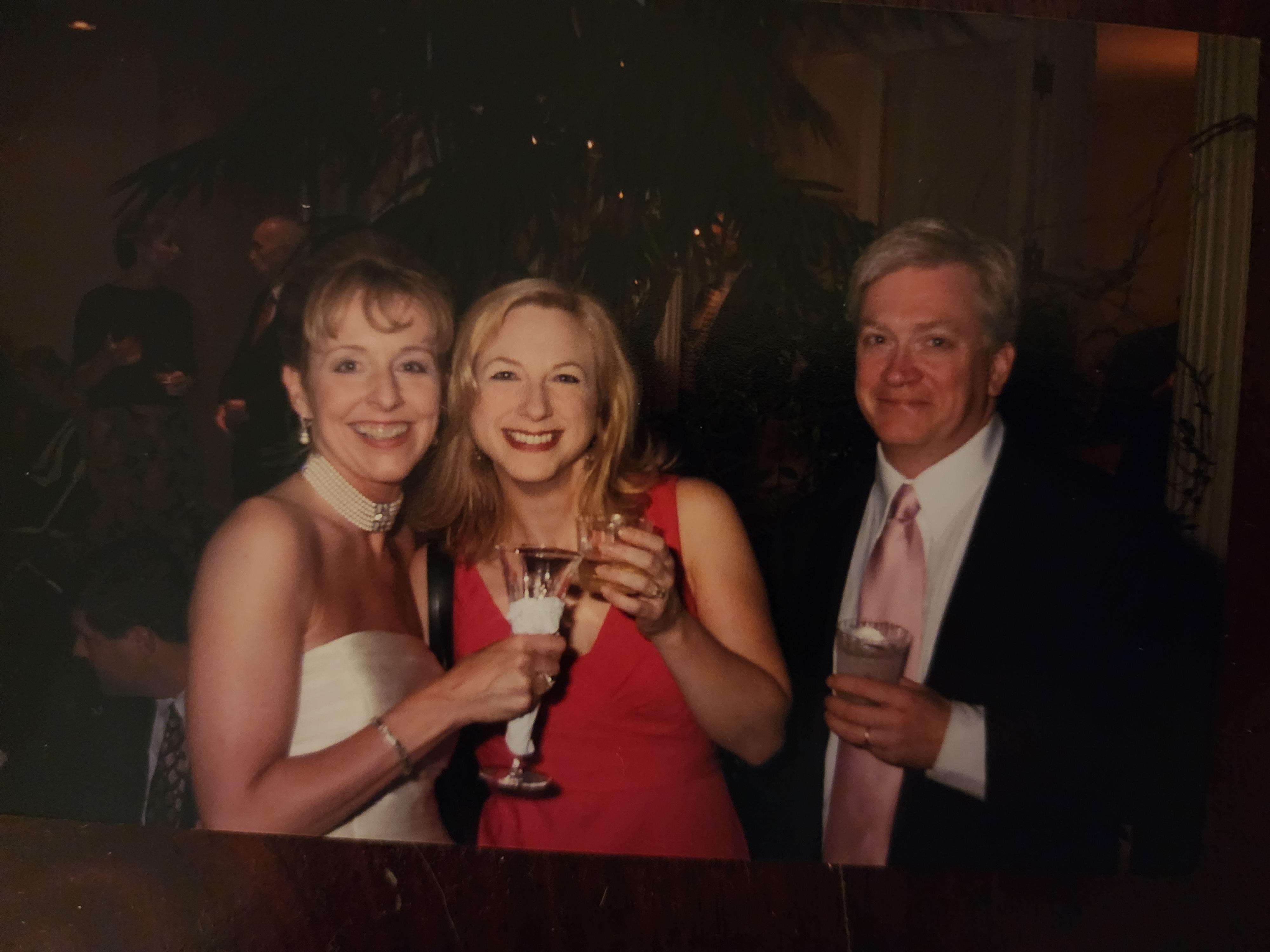 Three friends enjoy a moment at a joyful celebration, toasting with drinks in hand.