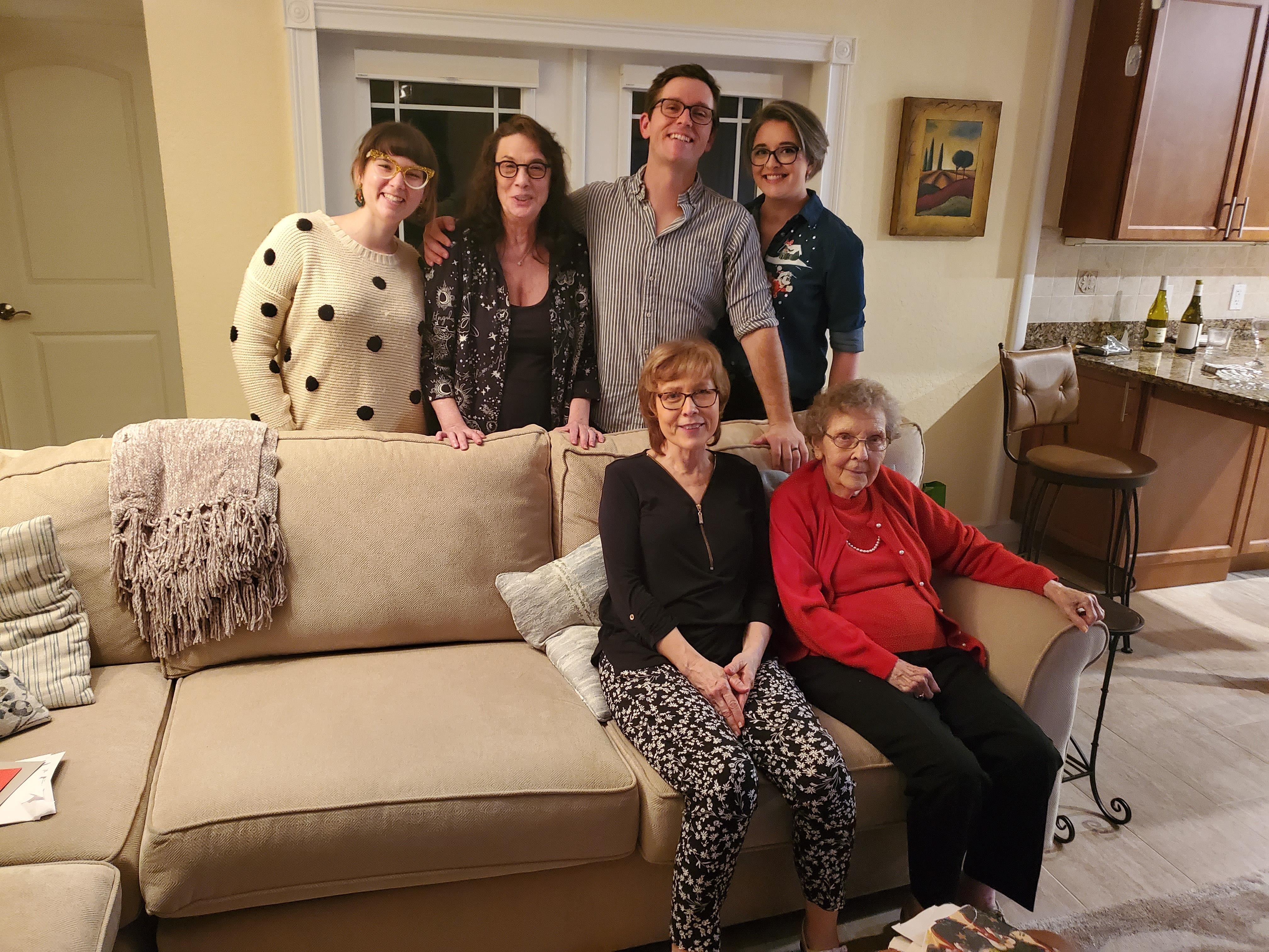 Six family members enjoy quality time together in a warm, inviting living room setting.