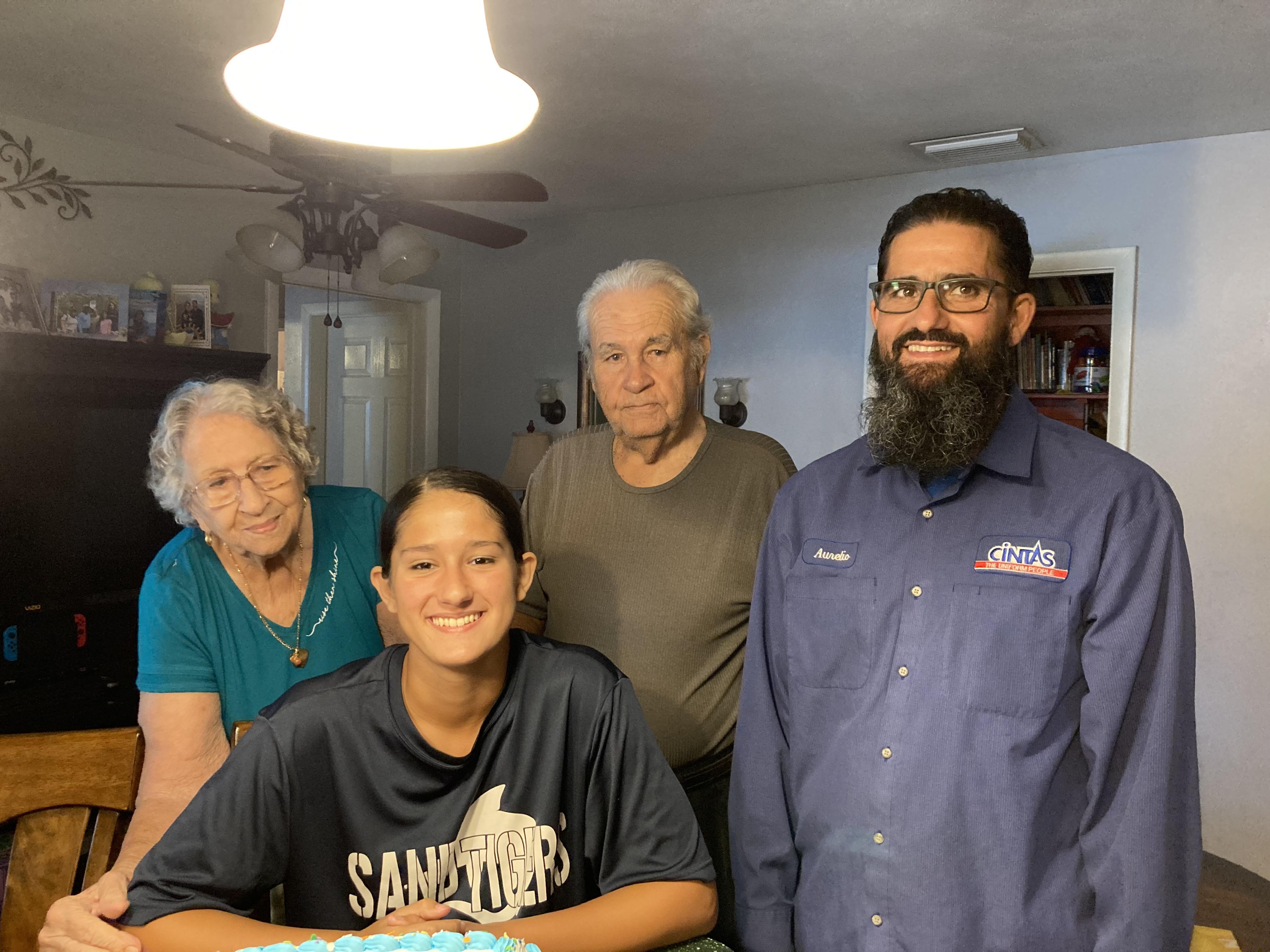 Four family members stand together in a warm kitchen, sharing smiles and enjoying a moment together.