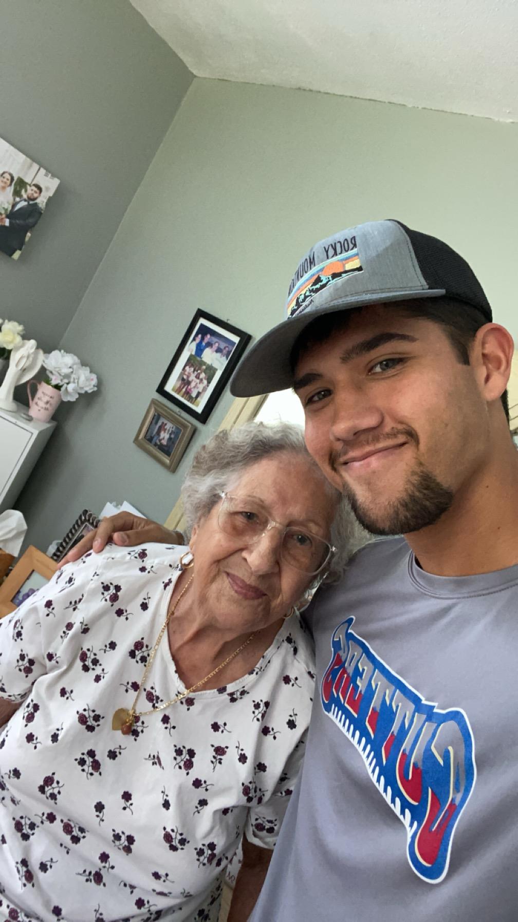 A grandmother and her grandson smile together in a warm living room, enjoying each other's company.