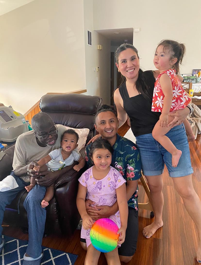 A warm family gathering takes place in a cozy living room with smiling faces and playful children.