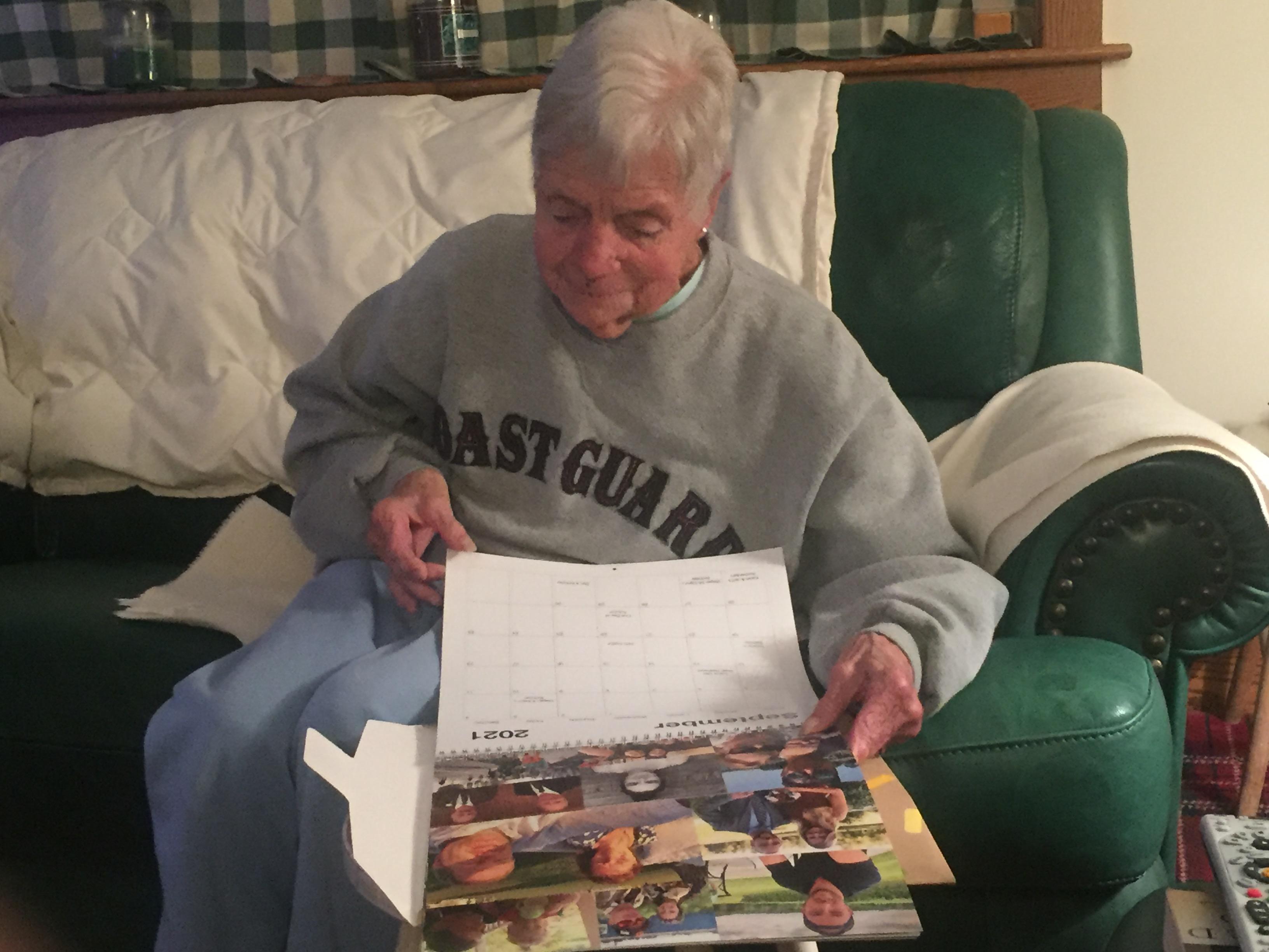Senior individual sits comfortably on a couch, examining a calendar filled with memories.