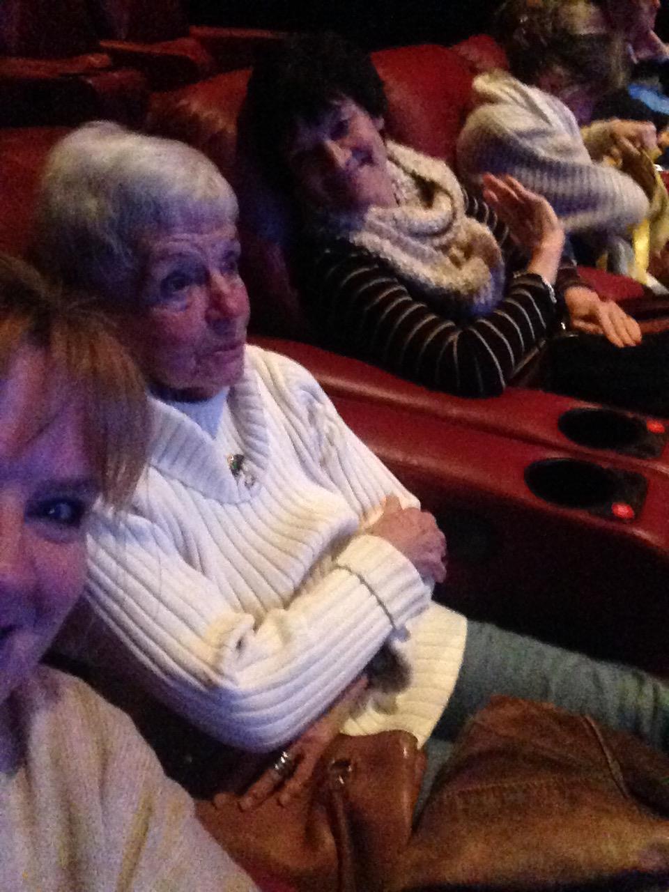 Friends gather for a fun movie night in a comfortable theater with plush seating and snacks.
