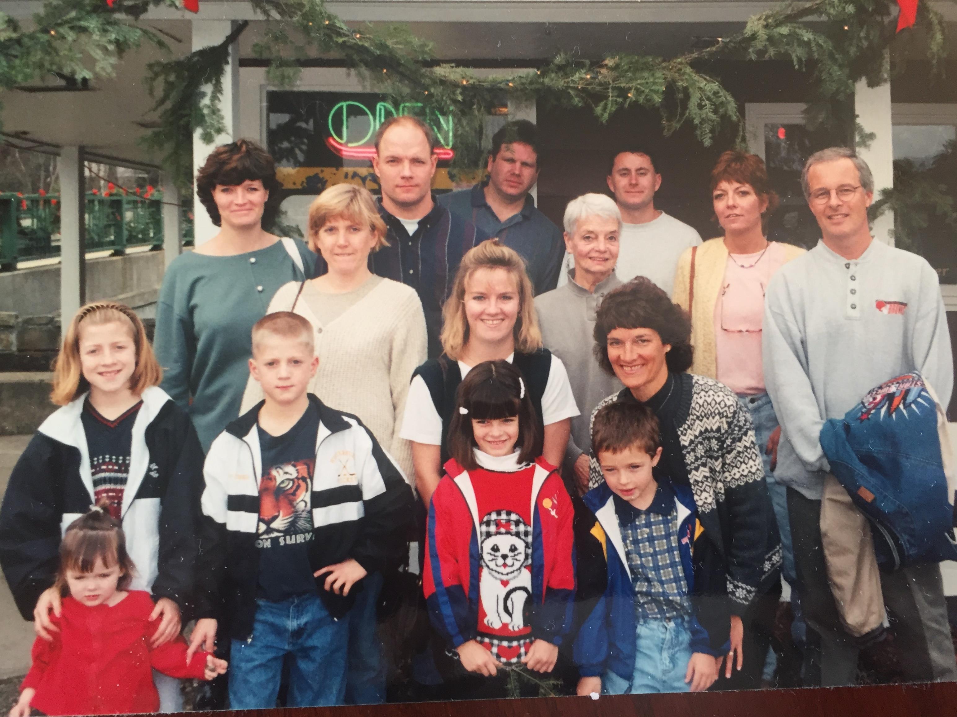 Group of family members posing cheerfully in front of a restaurant decorated for the holidays.