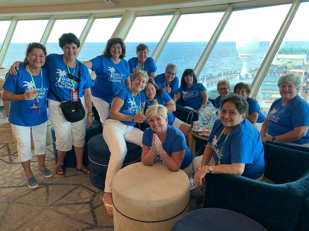 A cheerful group of women poses together on a cruise ship, enjoying their time at sea.