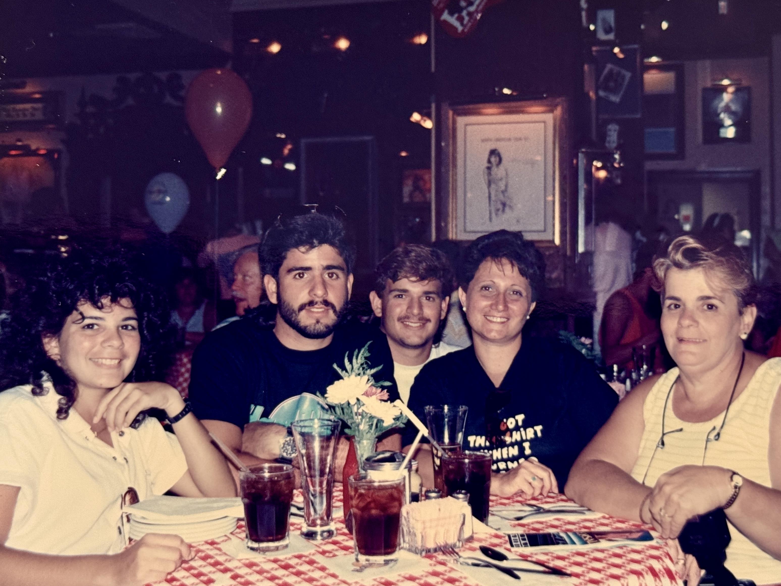 Friends are seated at a table, sharing drinks and laughter in a cheerful restaurant atmosphere.