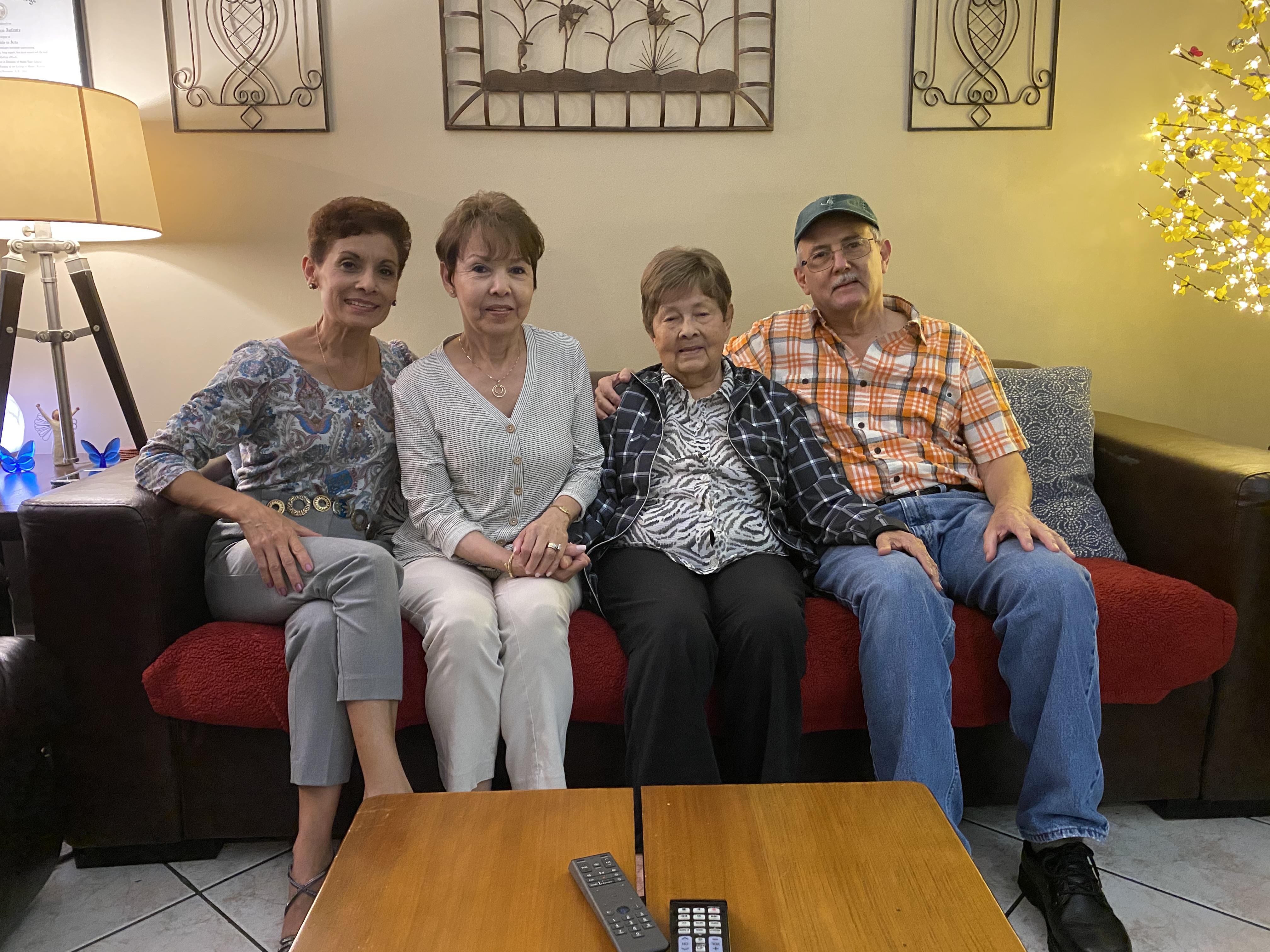 Four family members are seated on a couch, sharing quality time together in a warm setting.
