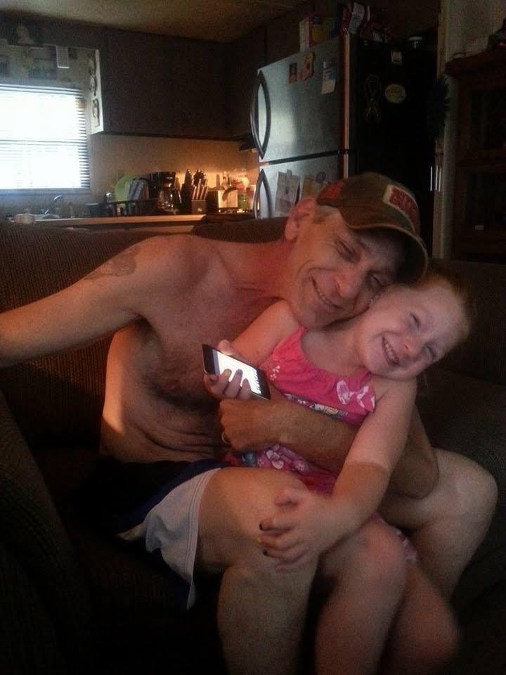 A grandfather hugs his granddaughter while they enjoy a warm moment in the living room.