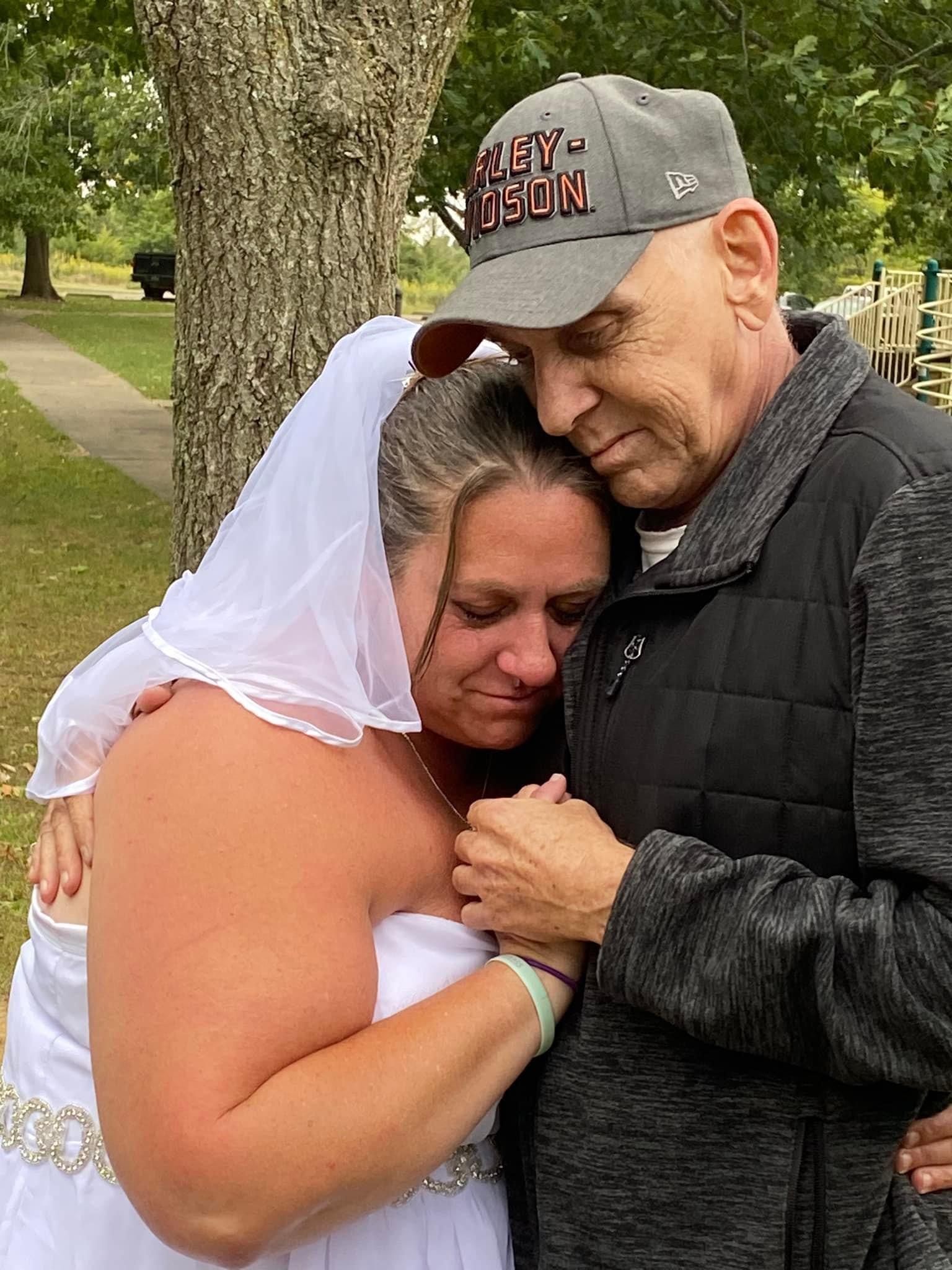Bride shares a touching moment with her father, celebrating love and family in the park.