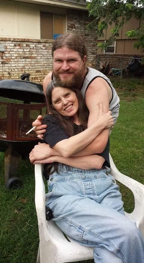 A couple sits outside on a lawn, enjoying their time together in a relaxed backyard setting.