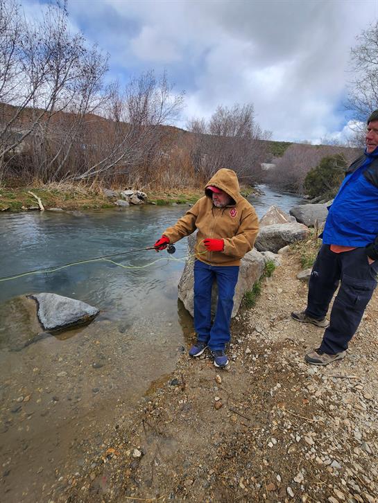 A man standing next to a man fishing