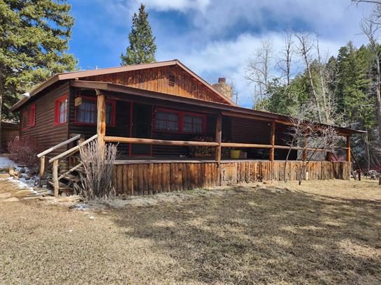 A log cabin with a porch and a fence