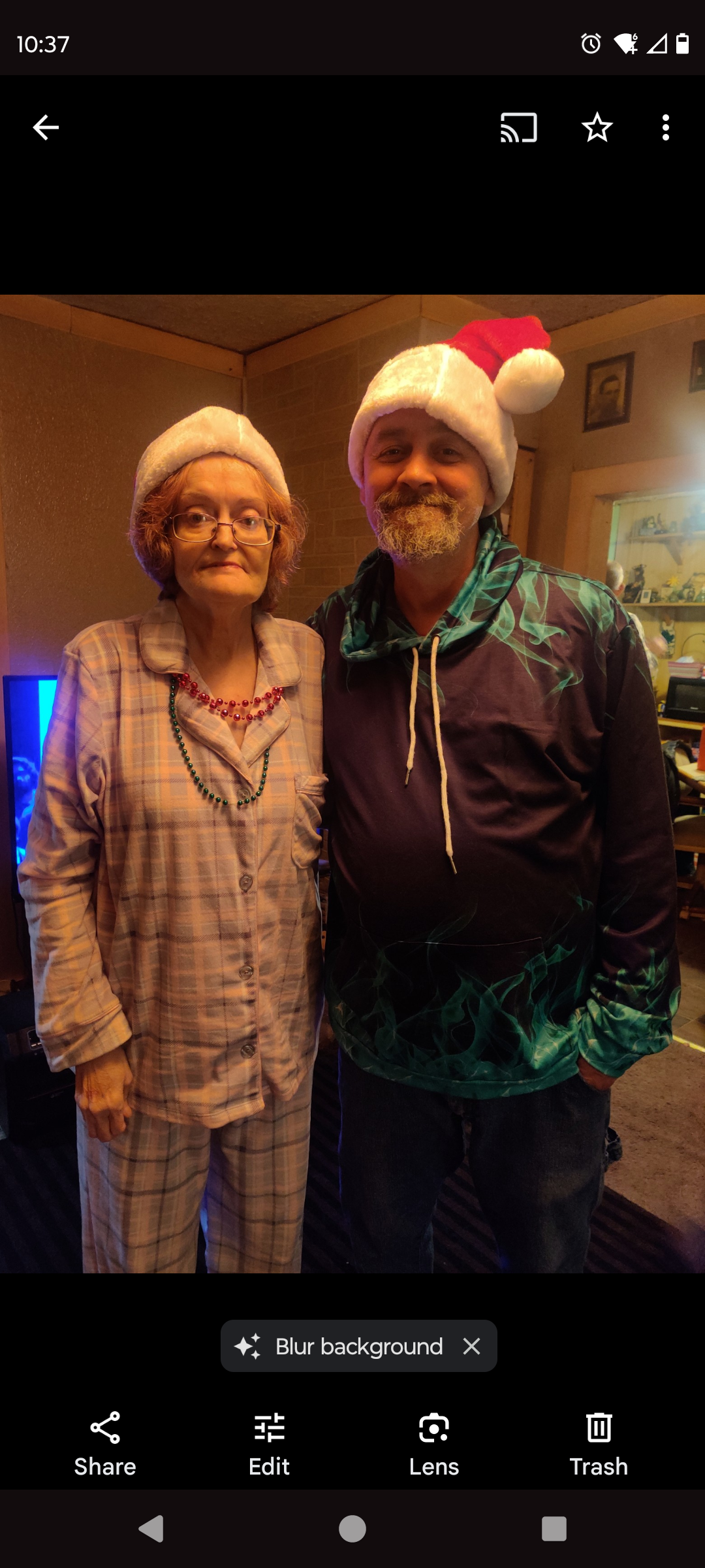 Family members wearing Santa hats and cozy pajamas enjoy a joyful holiday celebration indoors.