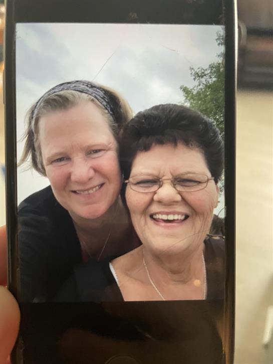 A woman smiling with her arm around another woman