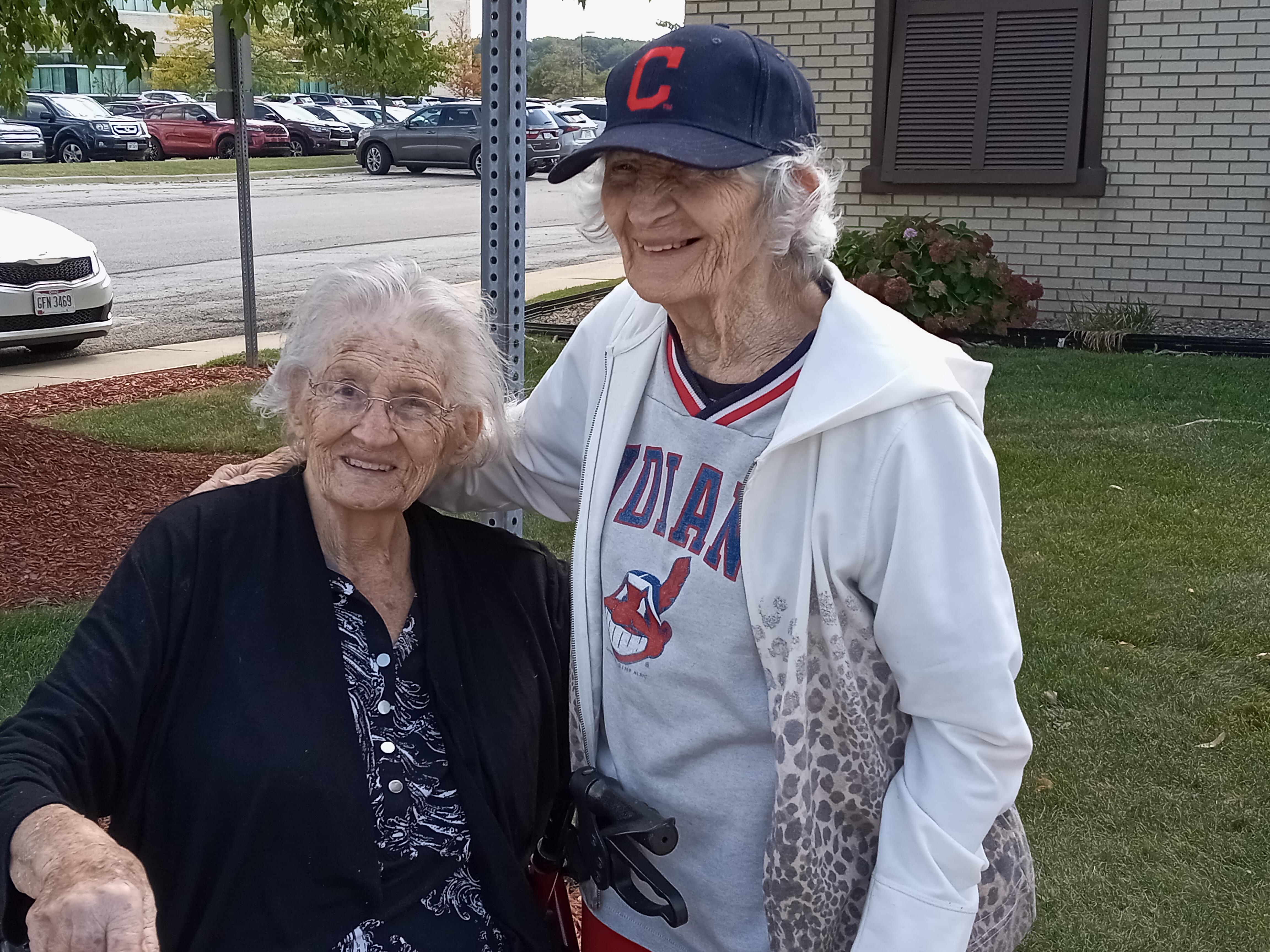 Elderly women enjoy each other's company, sharing smiles outside on a pleasant autumn day.