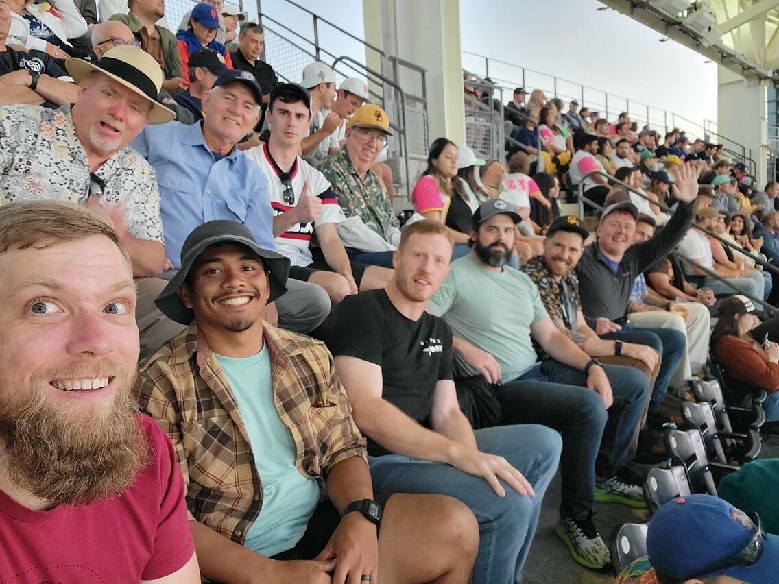 Friends gather together, smiling and cheering in the energetic atmosphere of a stadium.