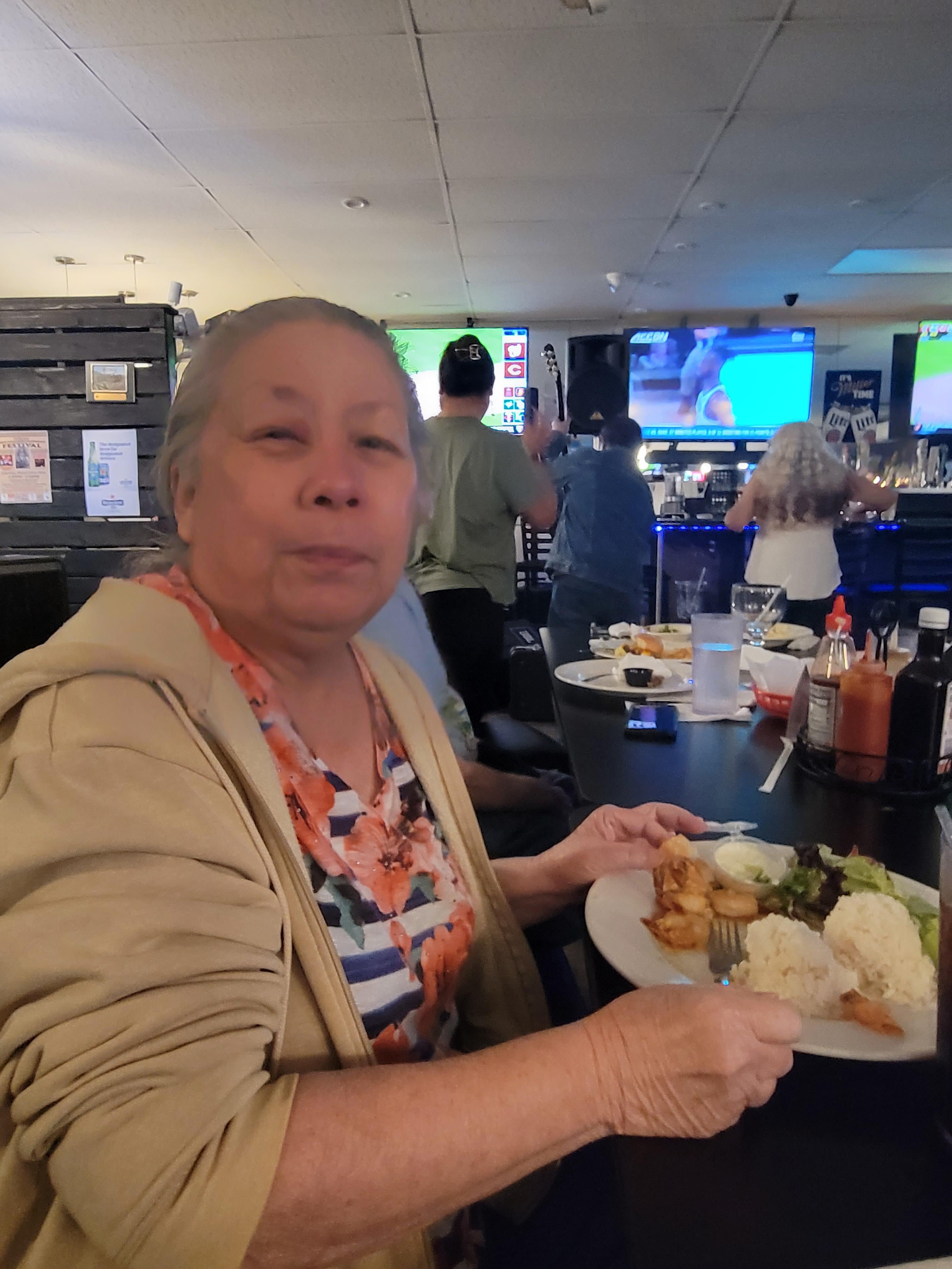 A woman enjoys a meal at a busy restaurant with friends.