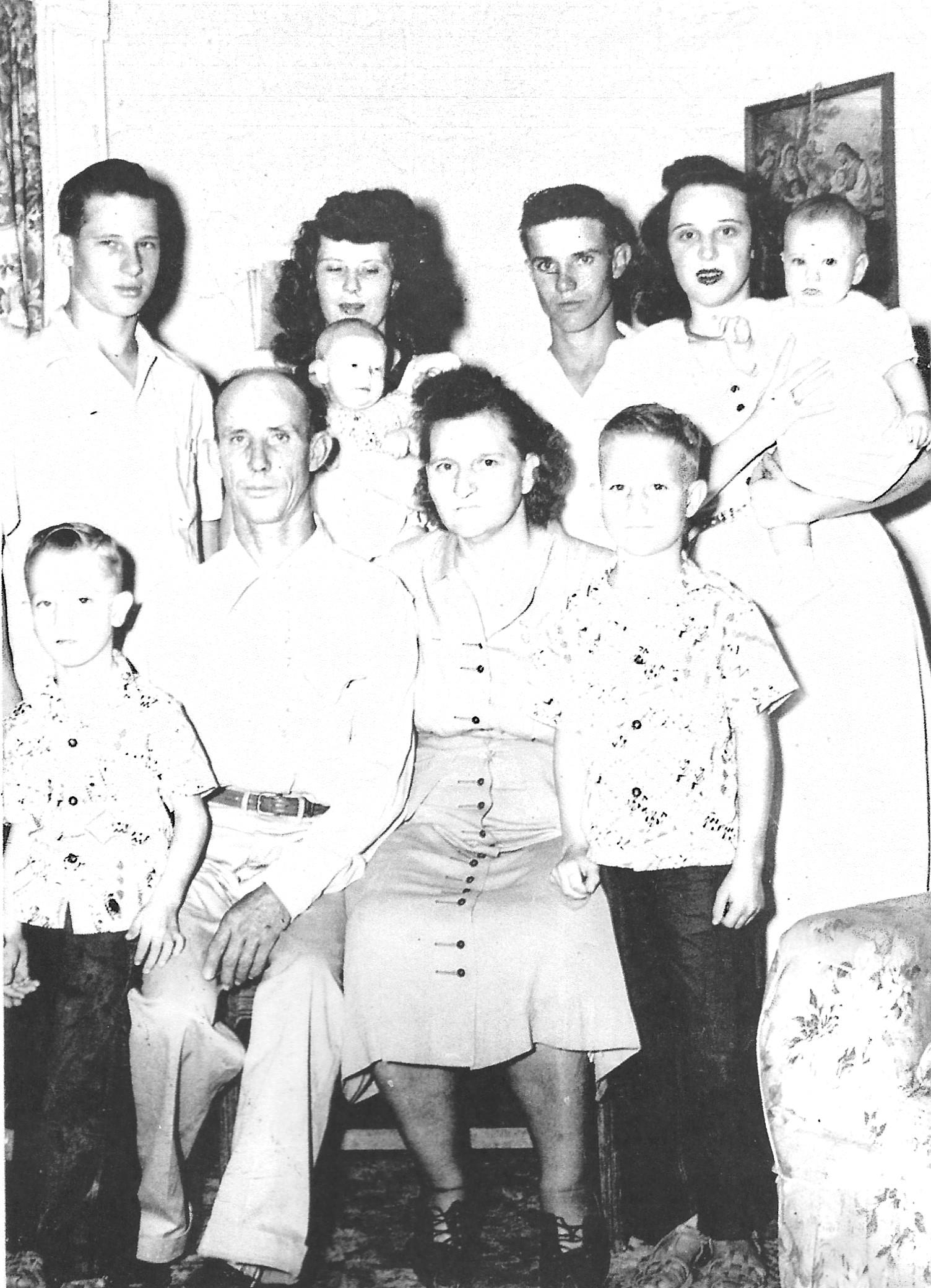 Group of family members smiling together in a cozy living room, showcasing different generations.