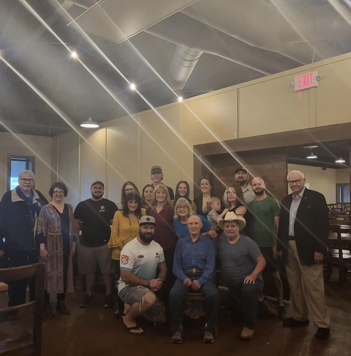 A diverse group of family members gathers in a rustic restaurant, smiling and celebrating together.