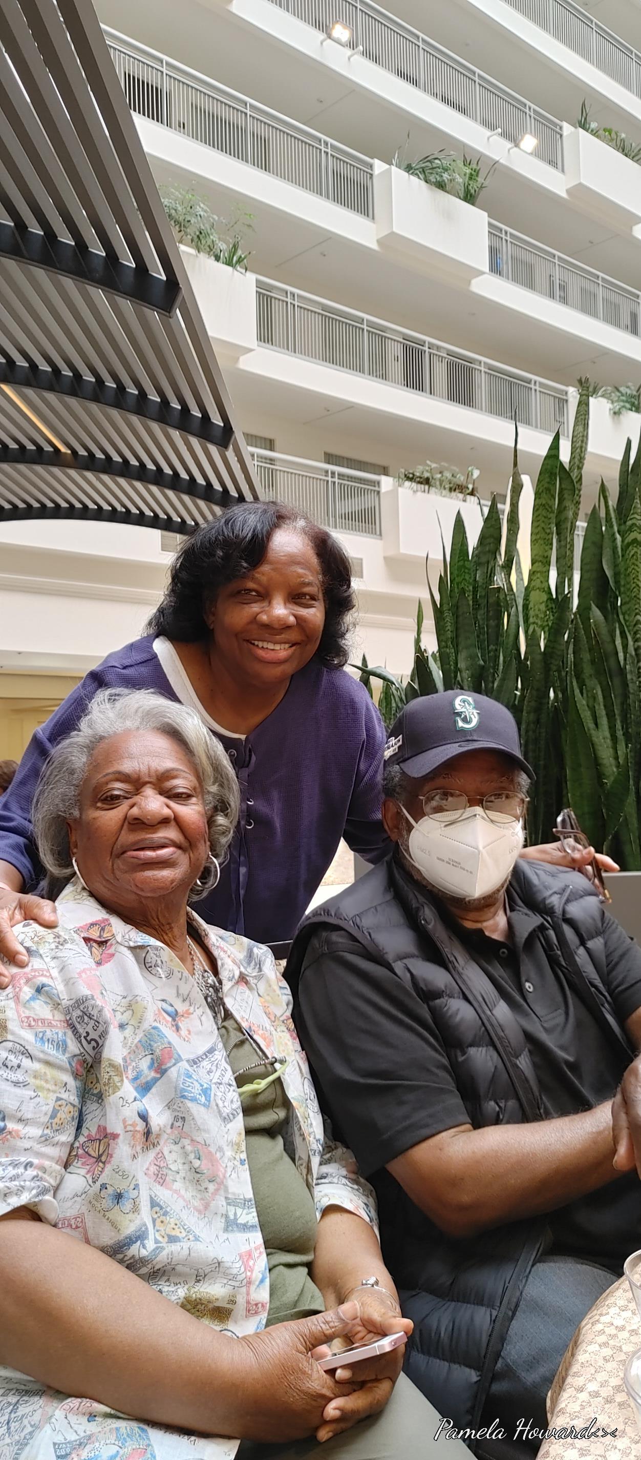 Three individuals share joyful moments together in an indoor garden setting, smiling and posing.