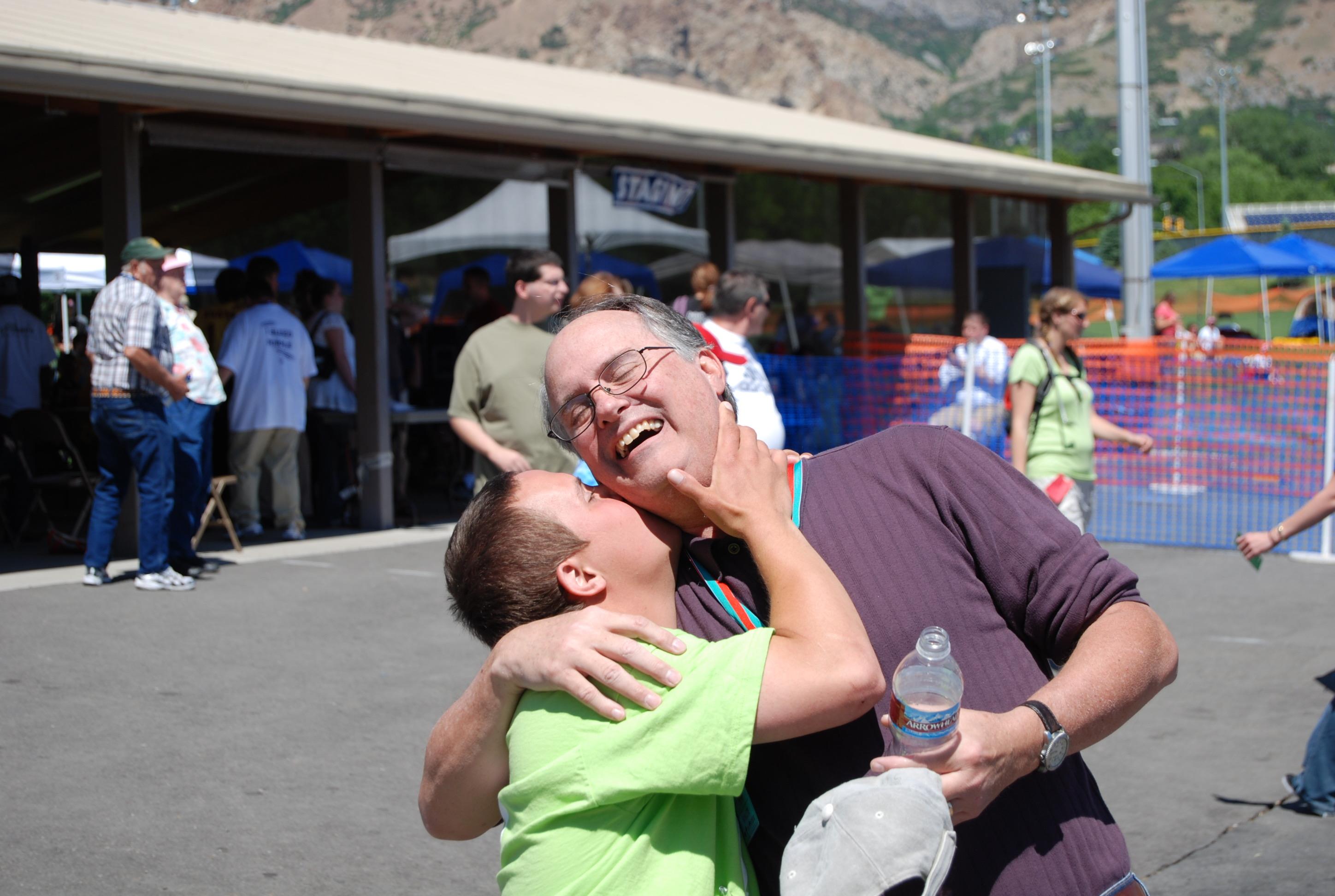 Two individuals share a happy moment, with laughter and warmth at a community gathering outdoors.
