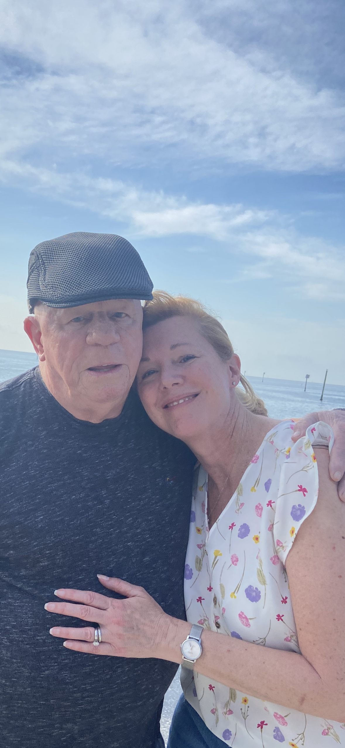 Two people enjoy a warm moment together on the sunny beachfront.