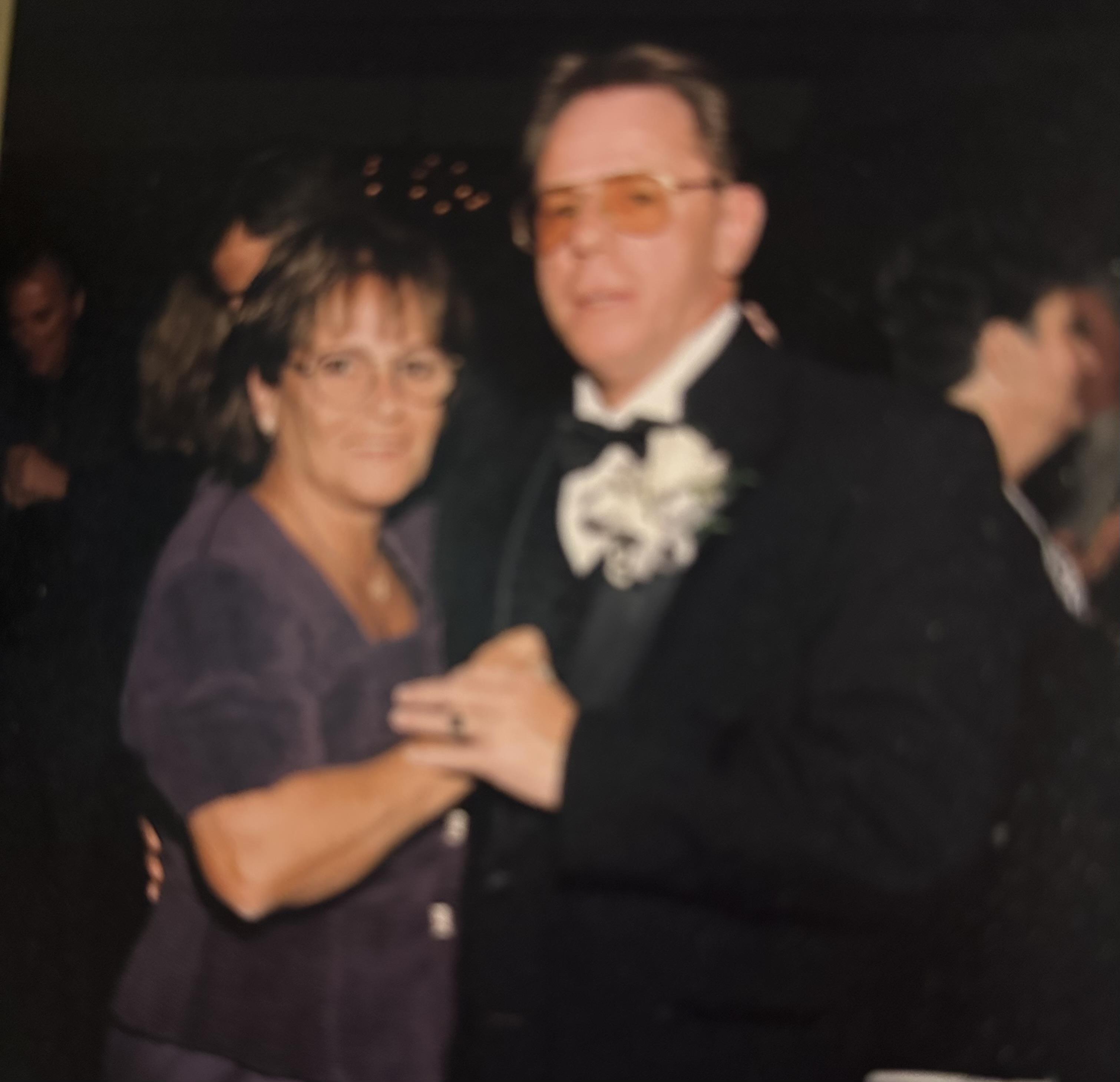 A couple enjoys a dance together at a formal gathering with friends nearby in the evening.