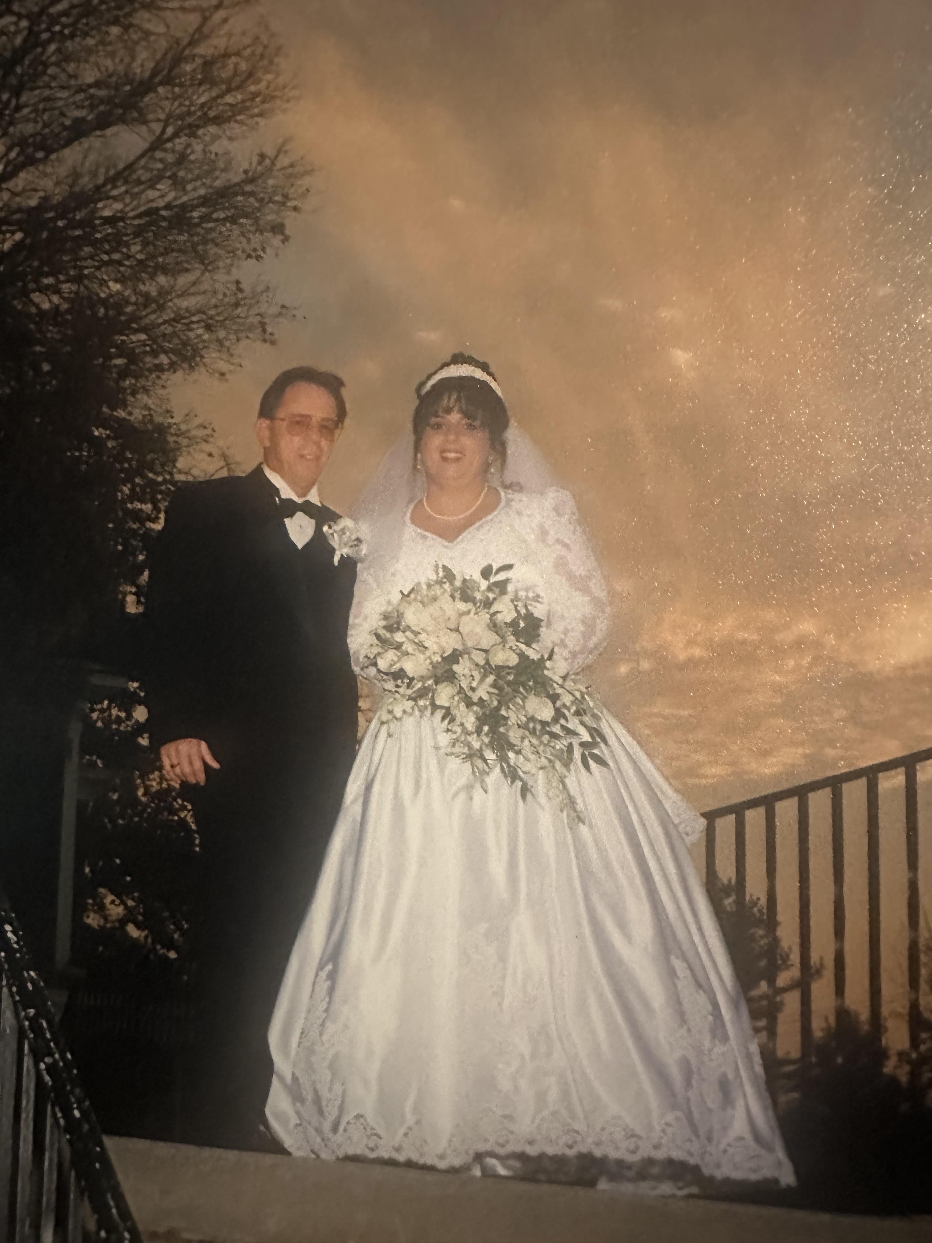 Bride and groom stand together on steps during sunset, surrounded by a scenic landscape.