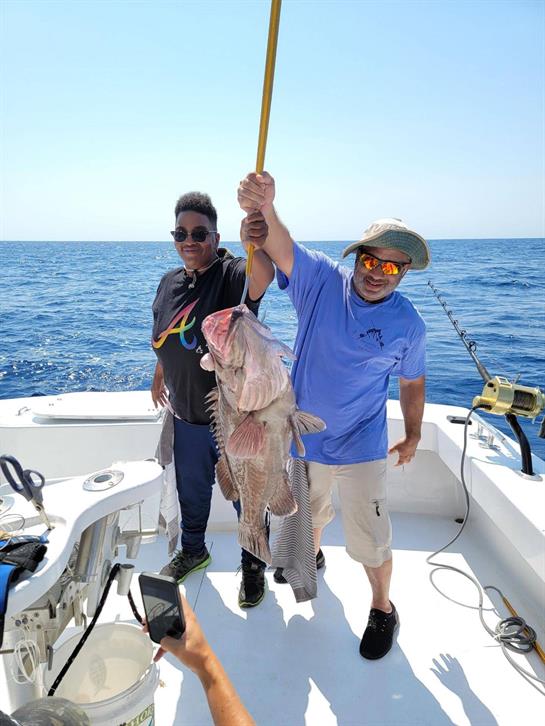 A man and woman holding a fish on a boat
