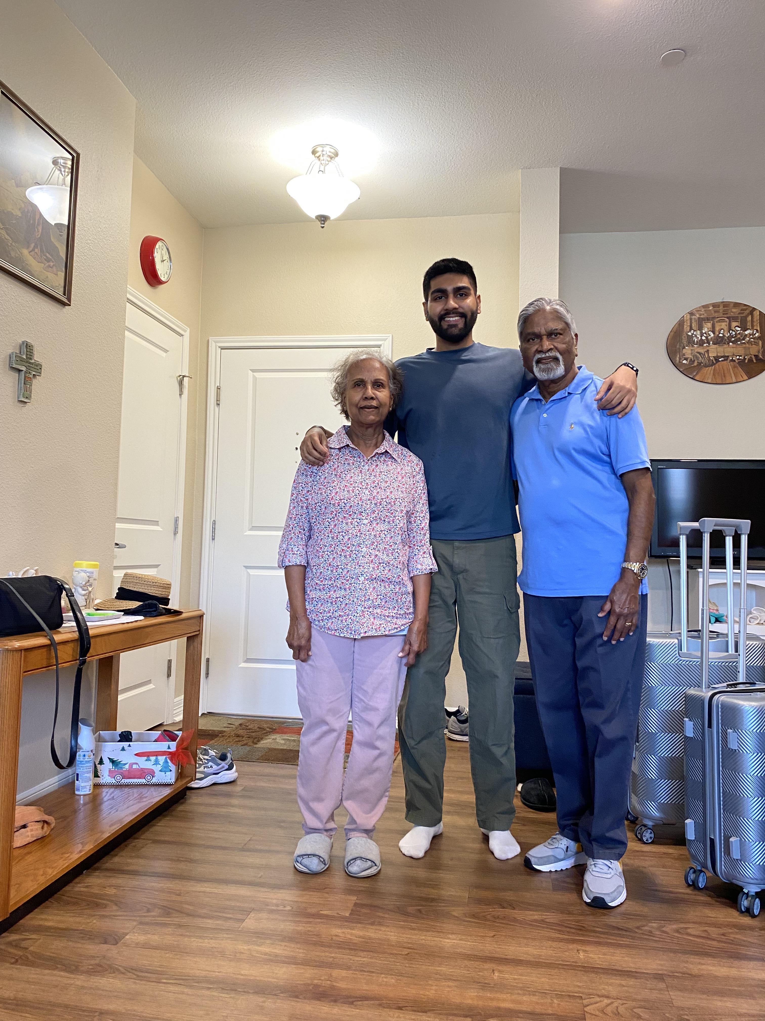 Three family members pose joyfully together in a bright and welcoming living room.