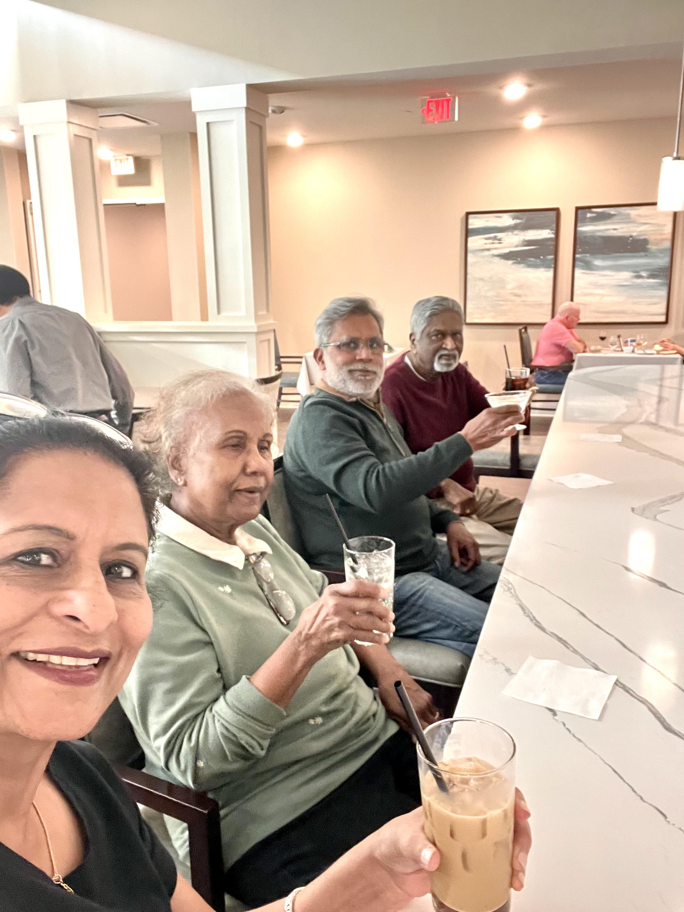 Friends share a joyful moment while sipping drinks at a cafe during the afternoon.