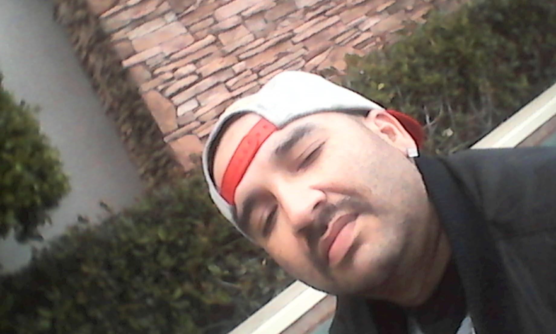 A man taking a break outdoors, sitting comfortably near a stone wall surrounded by greenery.