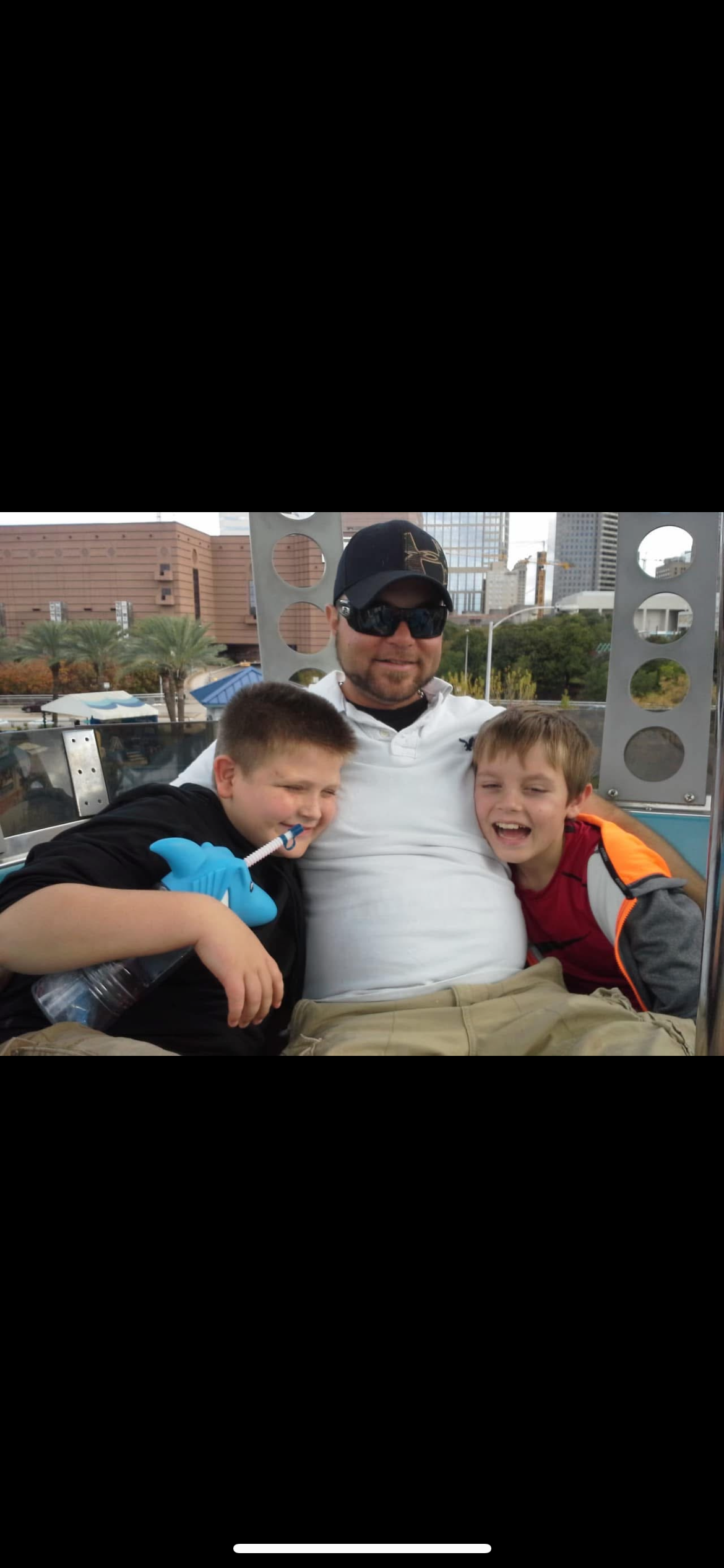Two children beam with joy riding with their father at the amusement park.